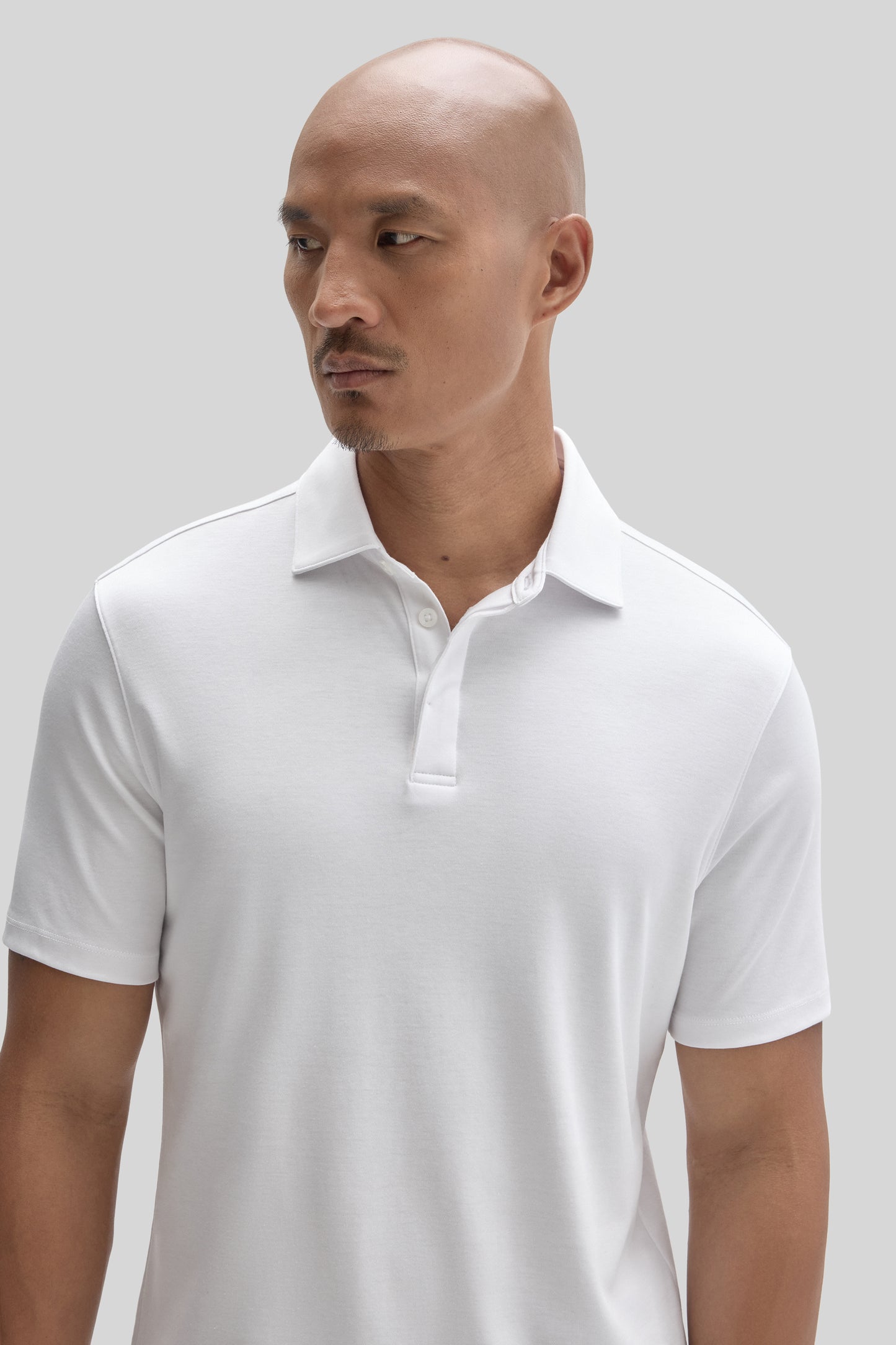 White polo shirt with covered placket and collar, shown on model.