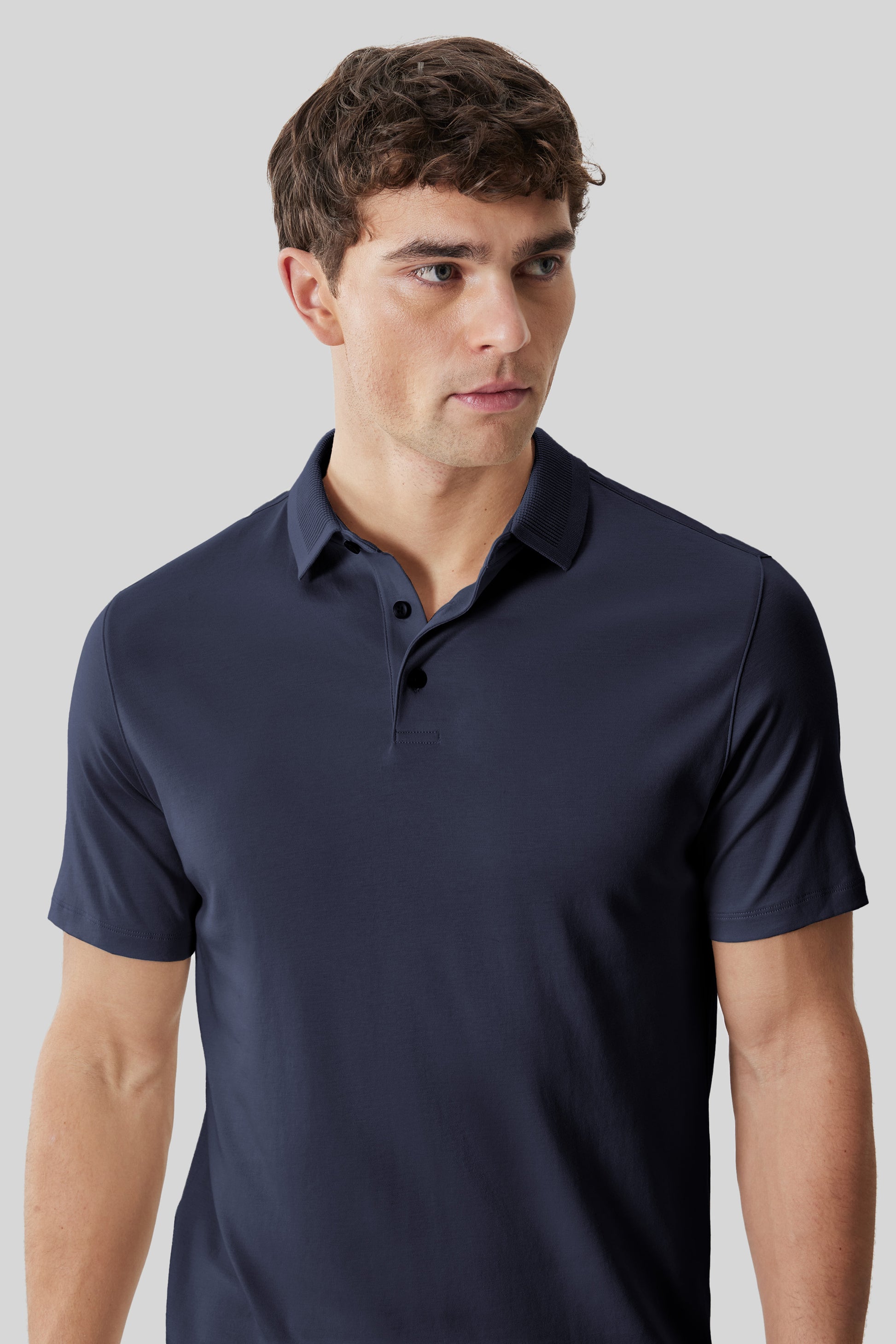 Man wearing a navy short-sleeve polo shirt with a textured collar and button placket.