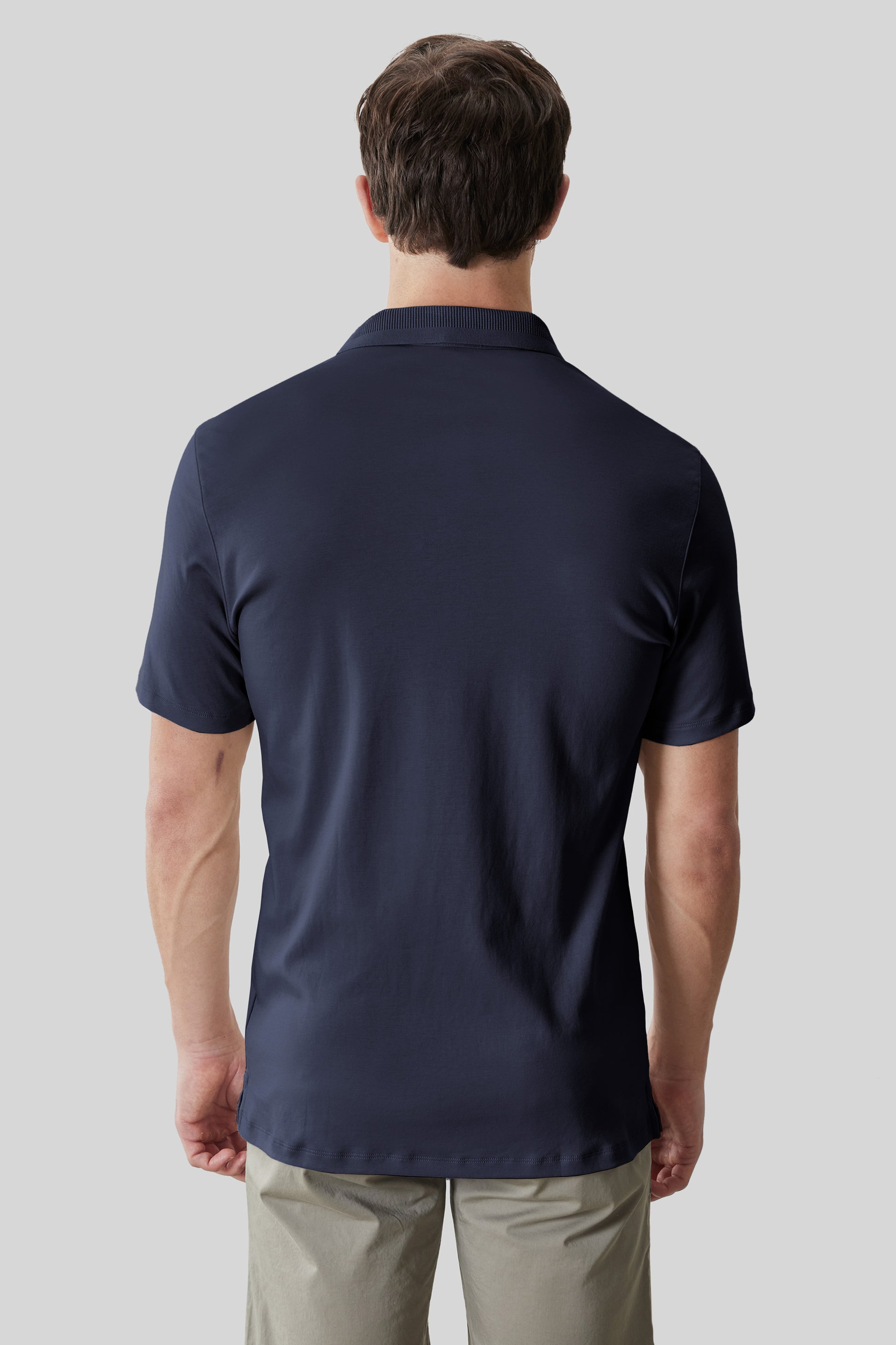 Navy short-sleeve polo shirt with textured collar, shown on male model from back view.