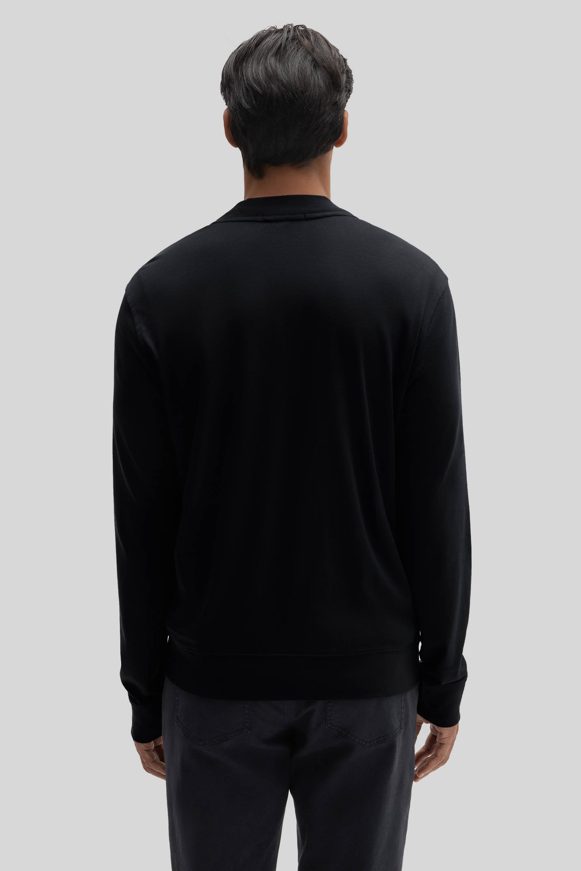 Black baseball jacket with collar and ribbed cuffs, shown from back view on model wearing dark pants.