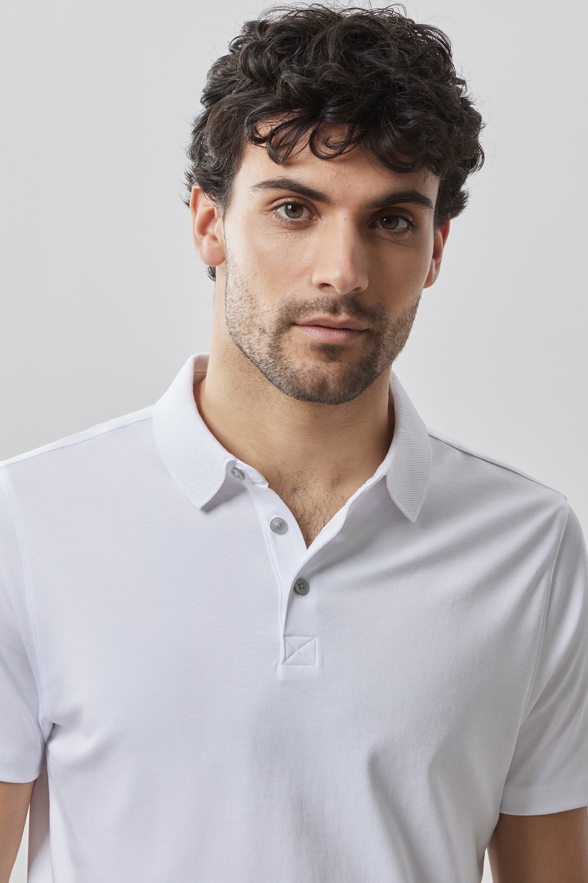 Man wearing a white short-sleeve polo shirt with a collared neckline and button placket.