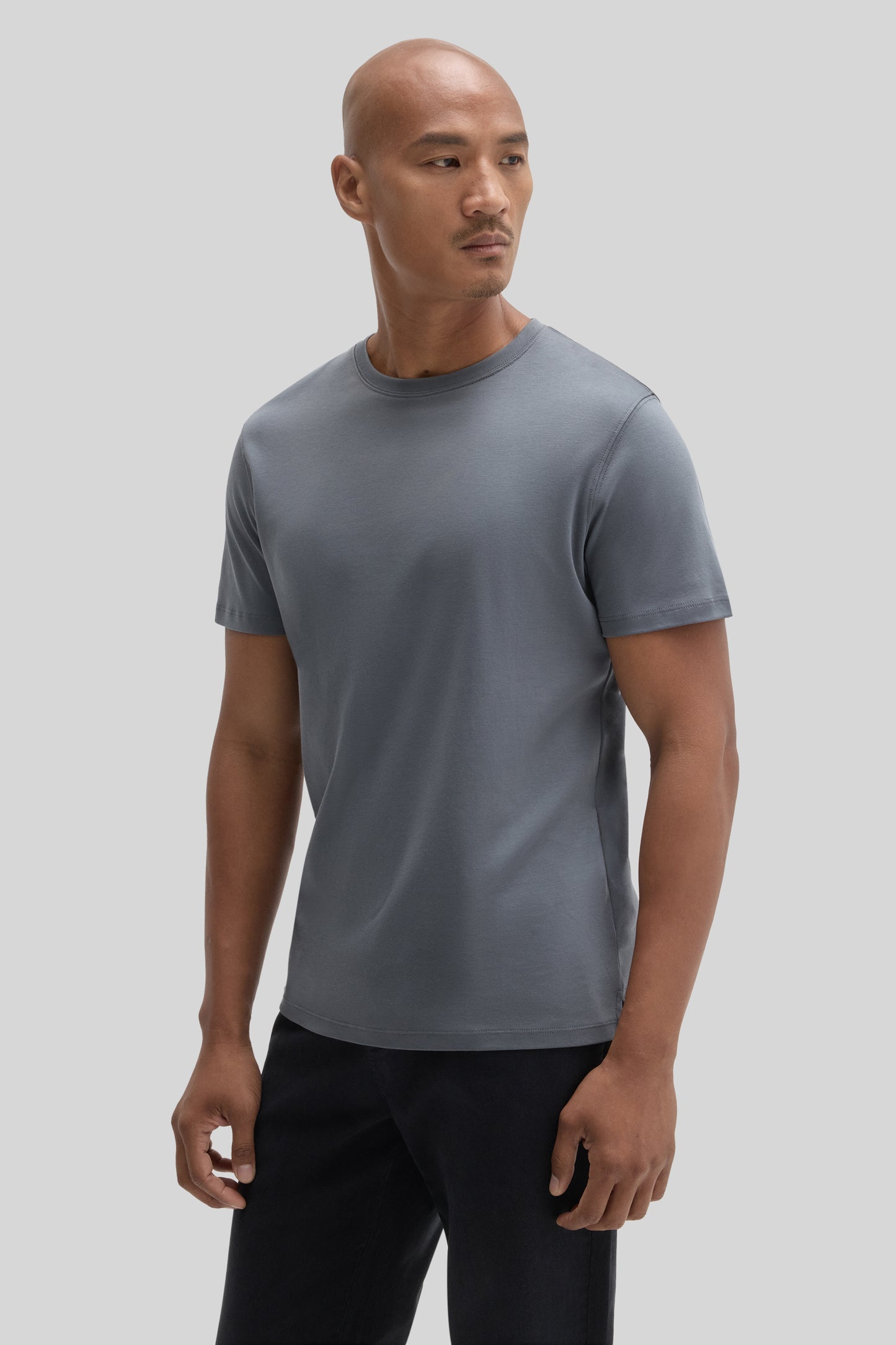 Man wearing a gray crewneck short-sleeve t-shirt with black pants.