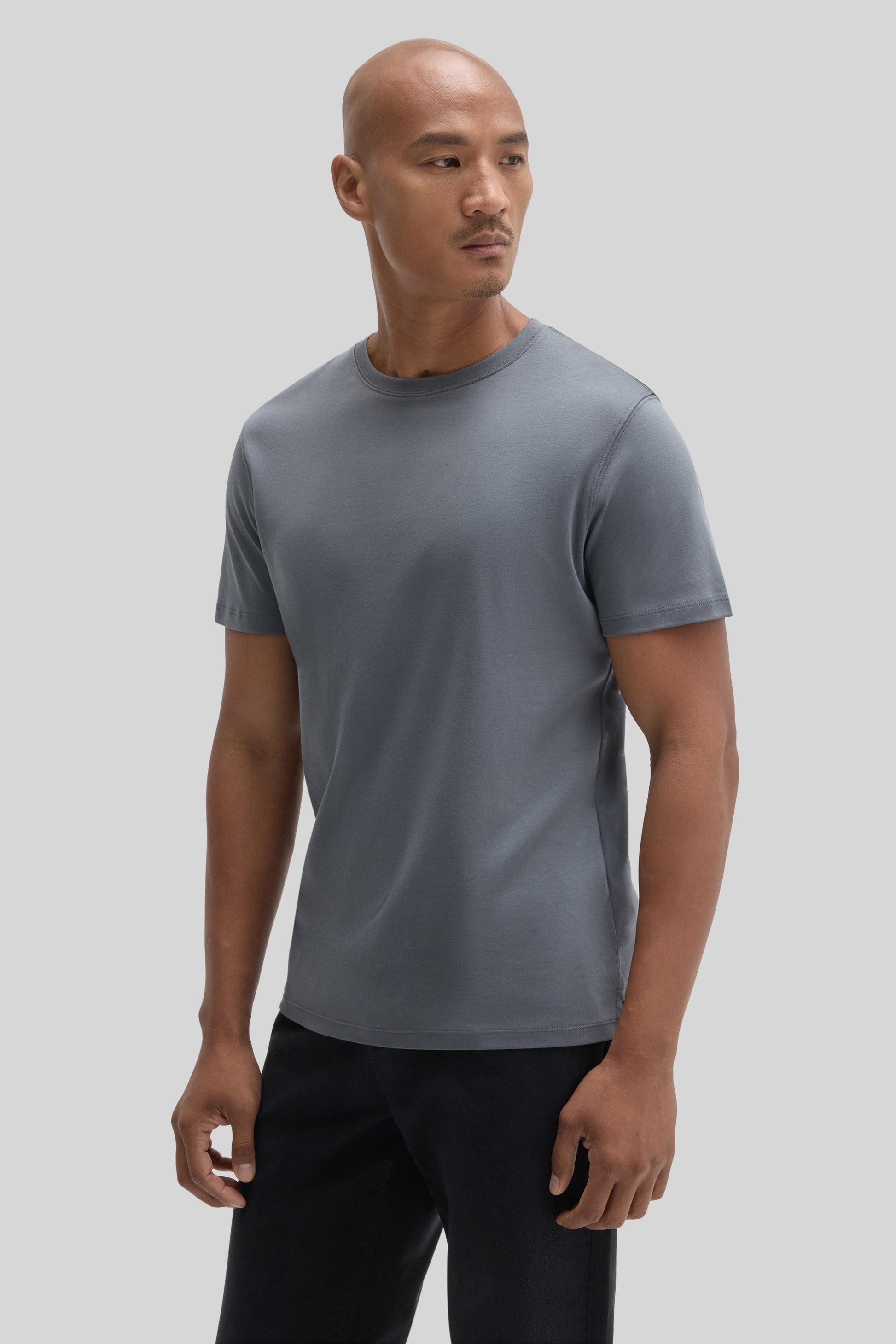 Man wearing a gray crewneck short-sleeve t-shirt with black pants.
