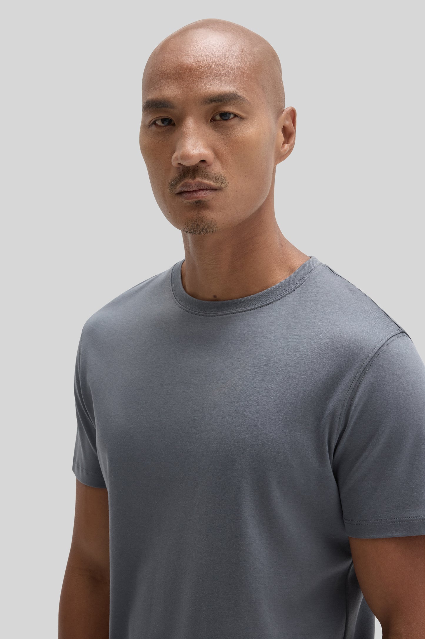 Man wearing a slate gray short-sleeve crew neck t-shirt against a neutral background.