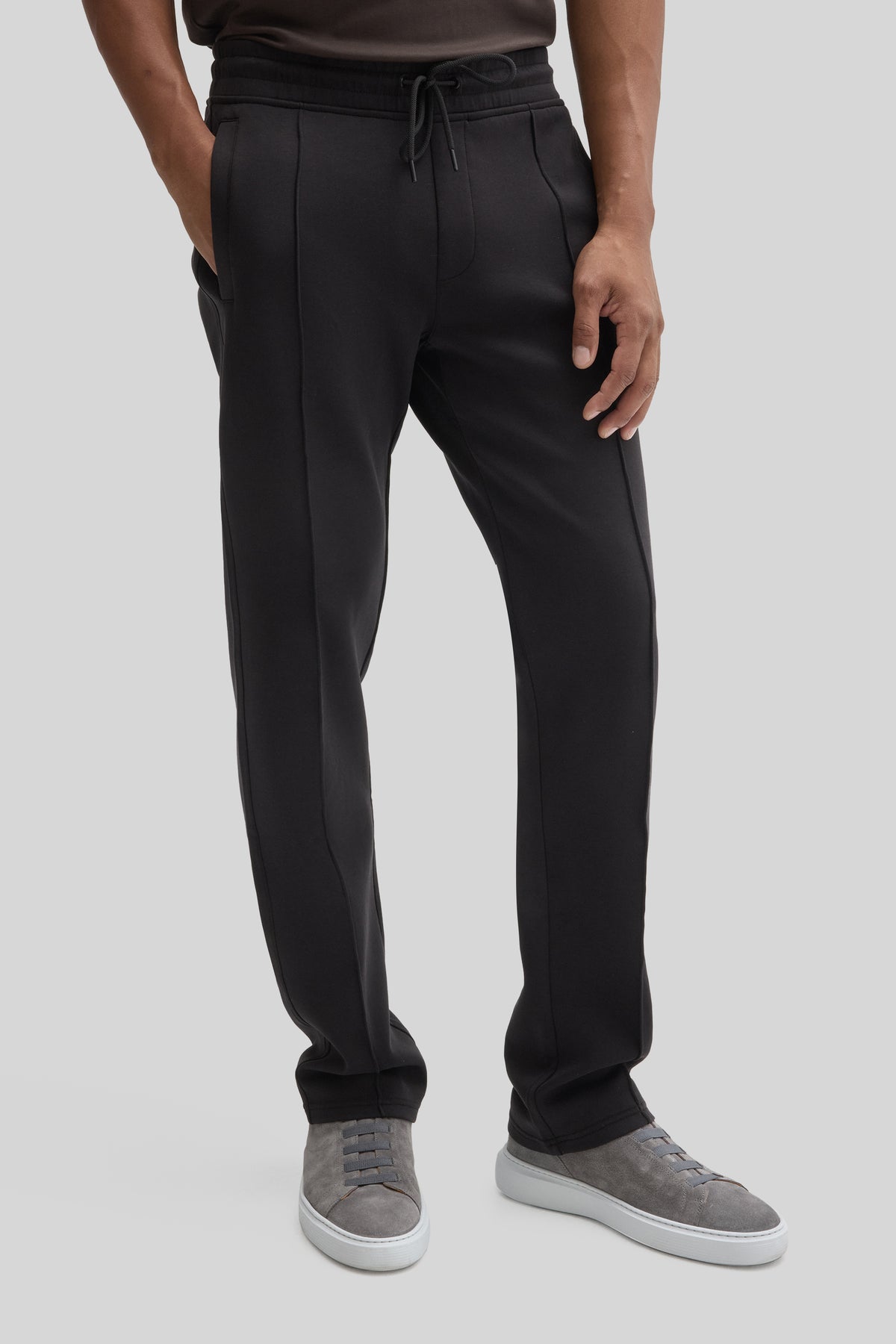 Black jogging pants with drawstring waist and center seam detail, worn with gray sneakers.