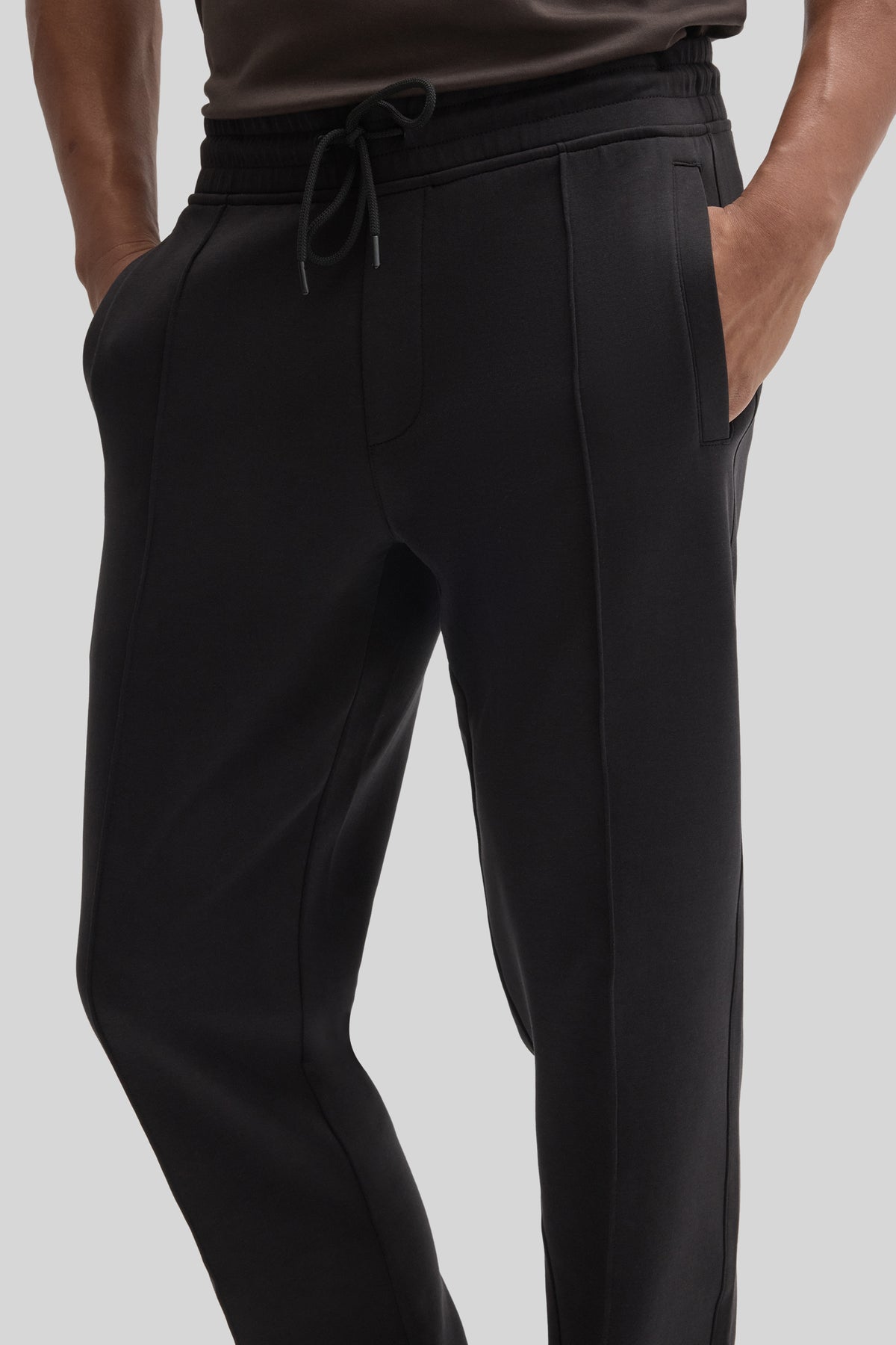 Black jogging pants with drawstring waist, side pockets, and tapered legs on a model.