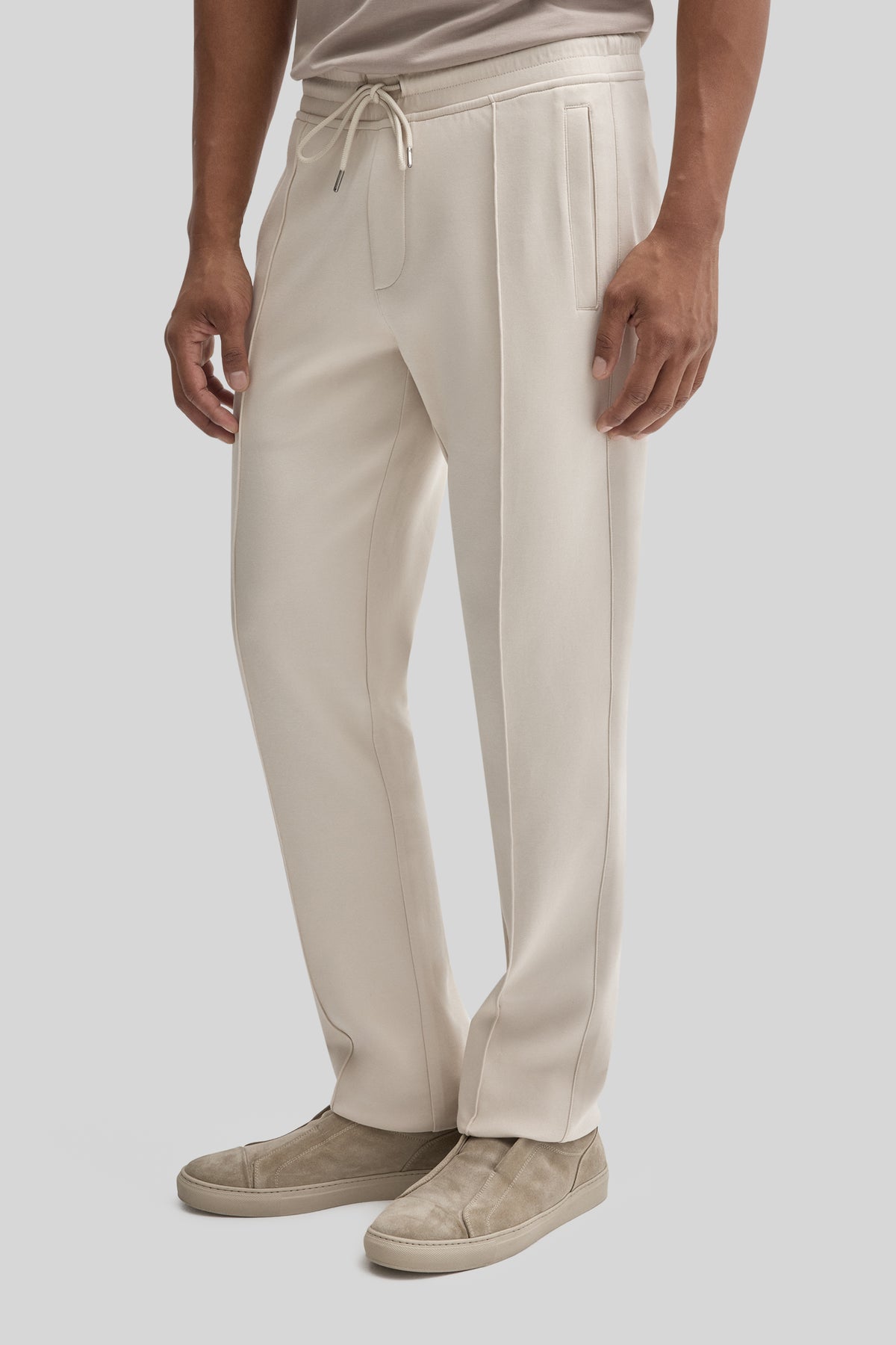 Cream-colored jogging pants with drawstring waist, side pockets, and contrast stitching on legs.