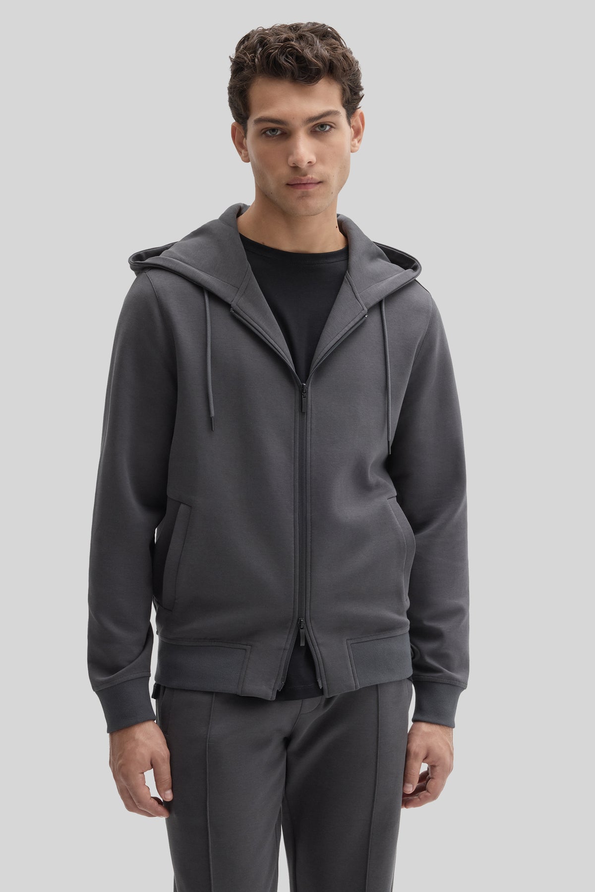 Charcoal gray full zip hoodie with drawstring hood and side pockets worn over a black shirt.