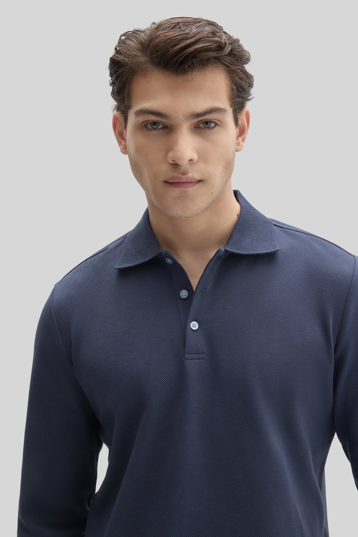 Navy long sleeve polo shirt with textured fabric and button placket worn by a man.