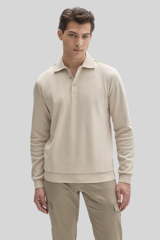 Man wearing cream-colored long sleeve polo with collar and button placket, paired with beige cargo pants.