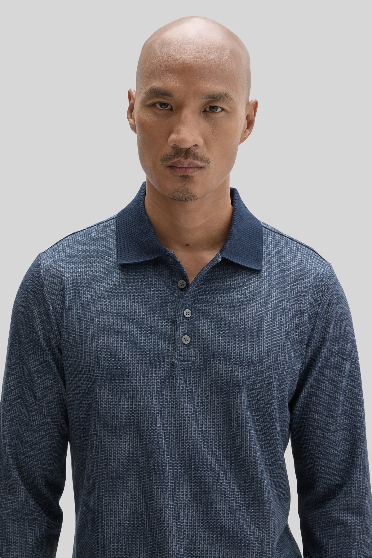 Man wearing navy blue long sleeve polo shirt with collar and button front.