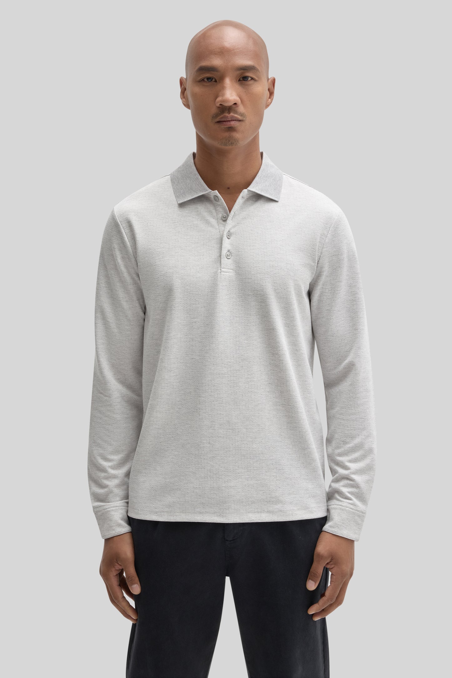 Light gray long sleeve polo shirt with button front and collar, worn with black pants.