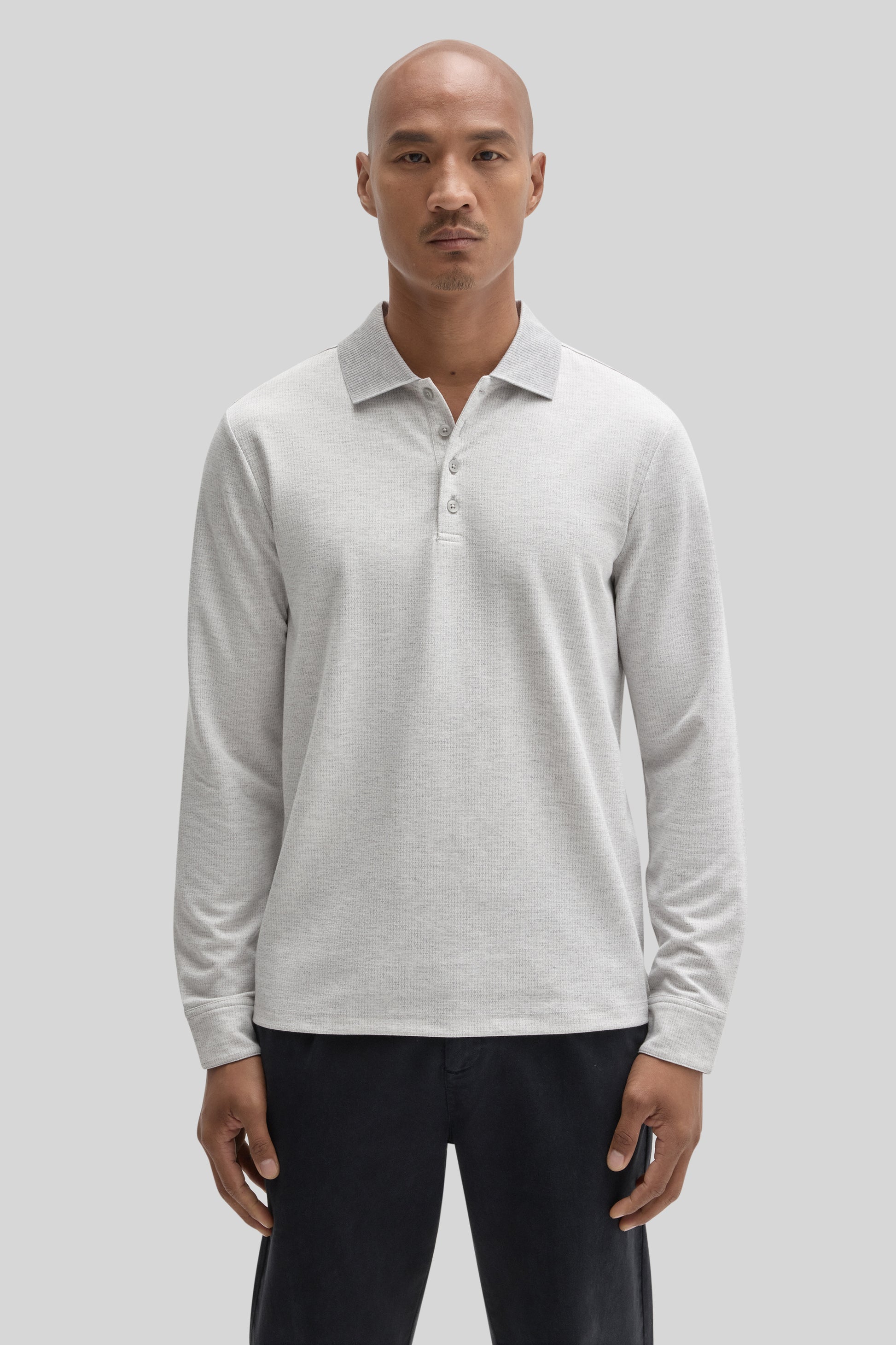 Light gray long sleeve polo shirt with button front and collar, worn with black pants.