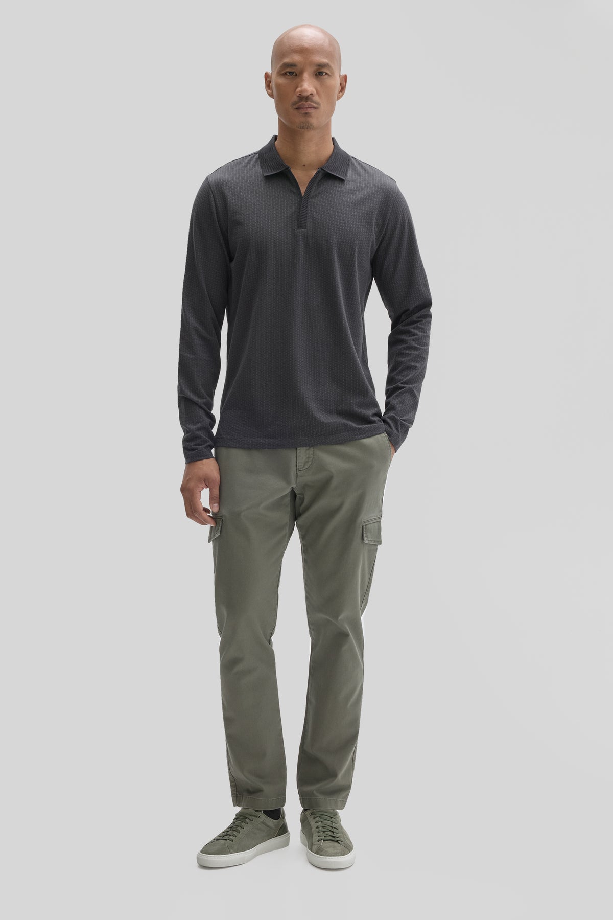 Man wearing charcoal long-sleeve polo with zip placket and sage cargo pants with matching sneakers.