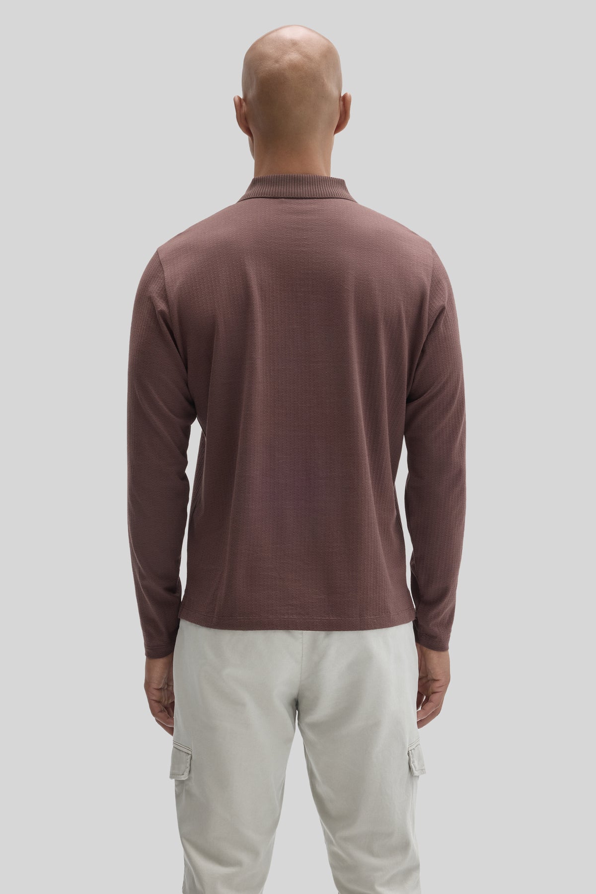 Mauve long sleeve polo with ribbed collar worn with cream cargo pants, shown from back view.