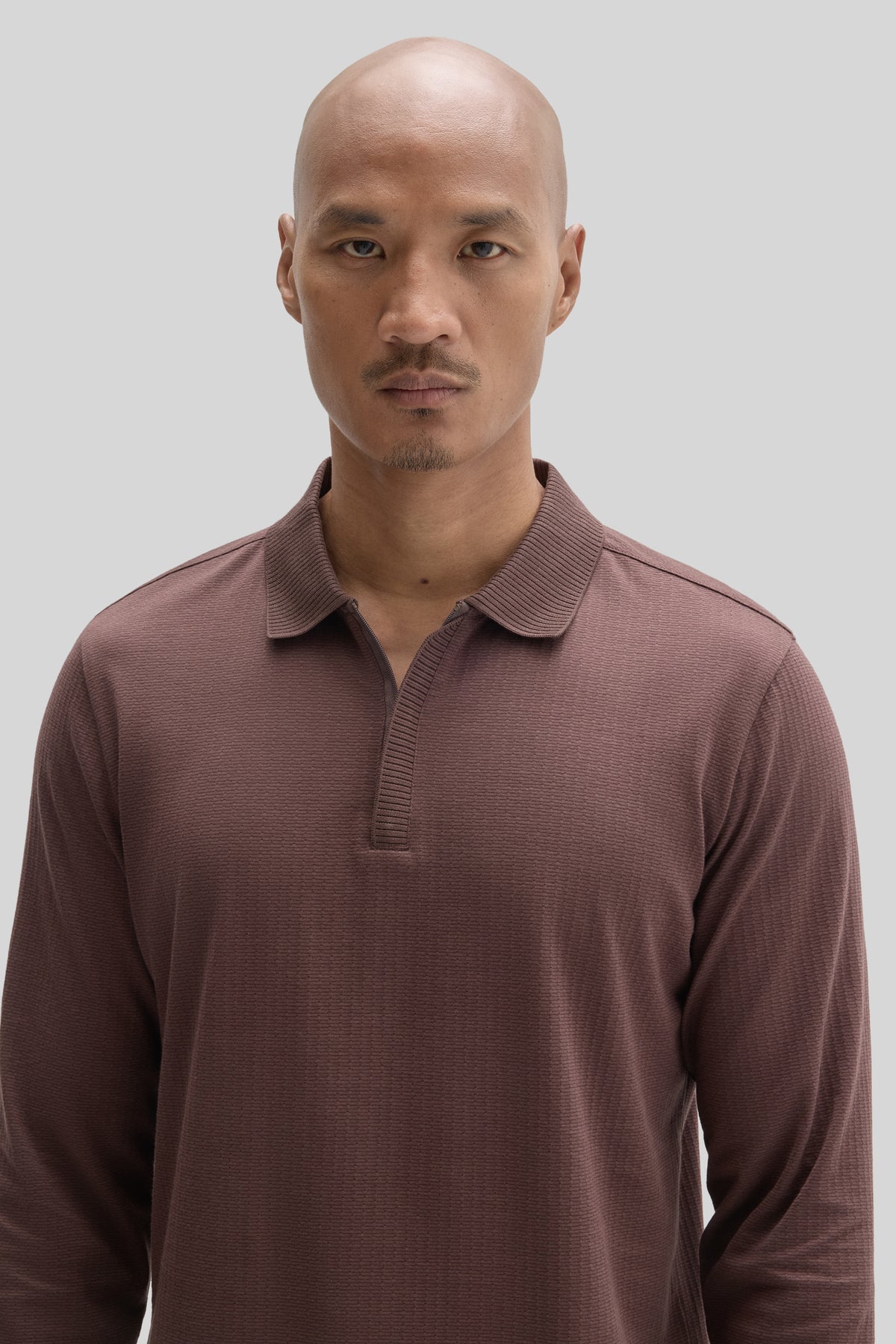 Mauve long-sleeve polo shirt with ribbed texture and zip placket neckline worn by model.