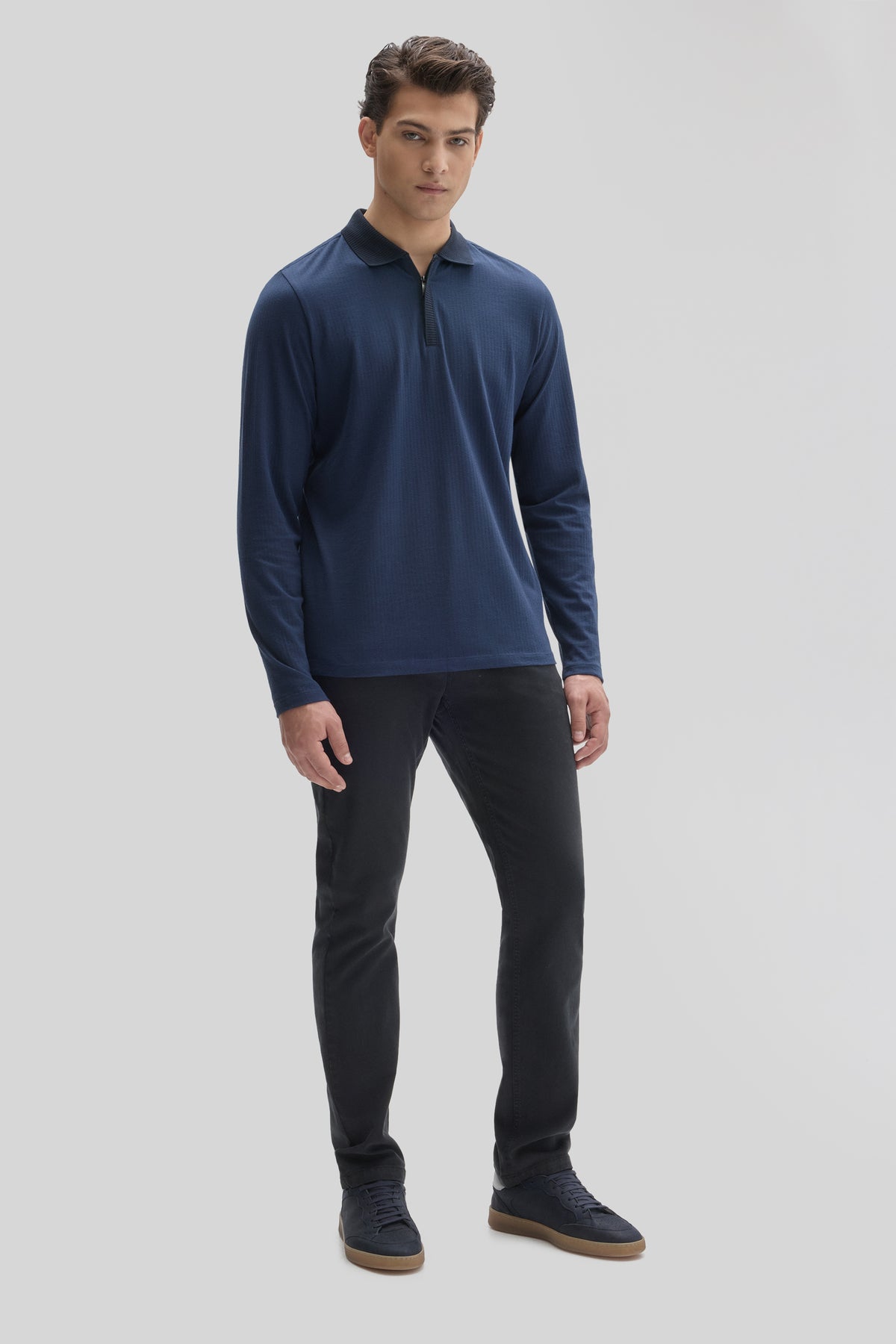 Navy long-sleeve polo shirt with zip placket and ribbed texture worn with black pants.