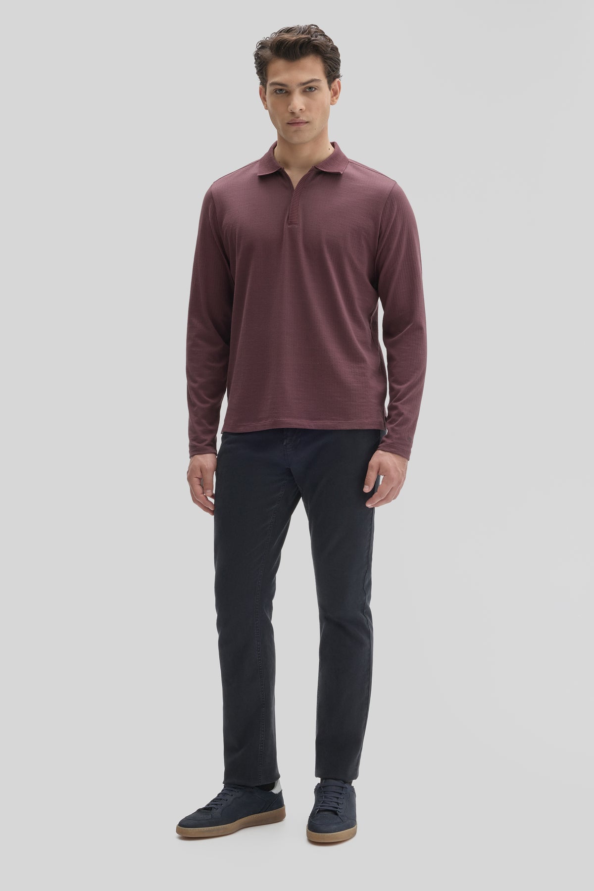 Man wearing burgundy long-sleeve polo with placket zip and dark jeans.