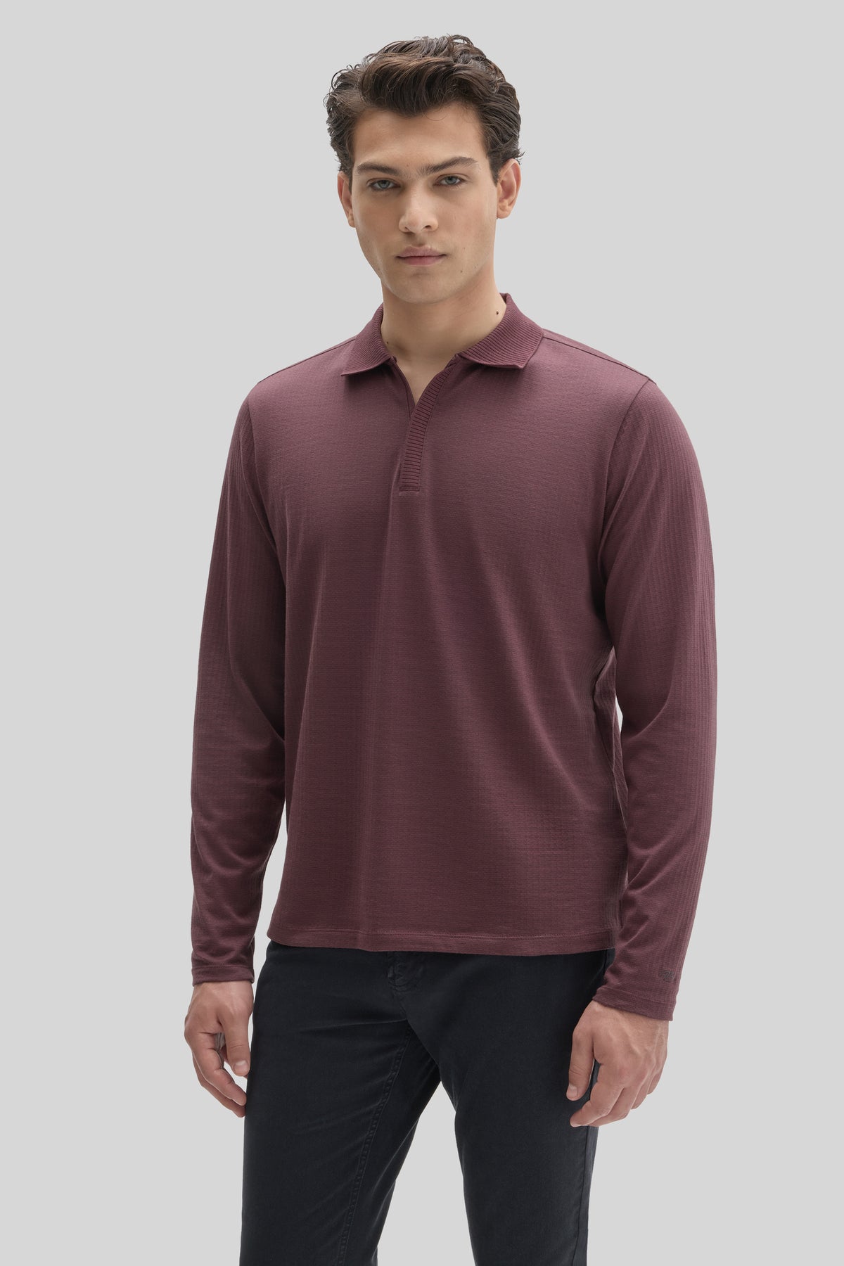 Burgundy long-sleeve polo shirt with placket zip neckline and ribbed texture, worn with dark pants.