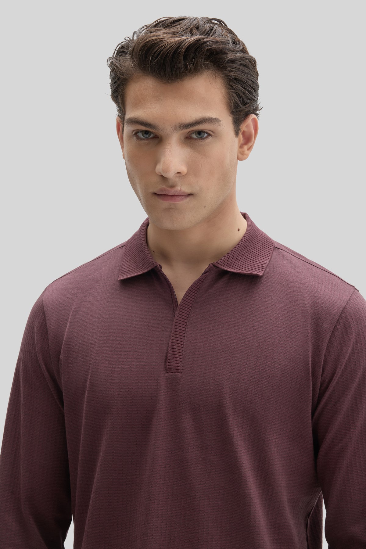 Man wearing burgundy long sleeve polo shirt with placket zip closure and ribbed collar.
