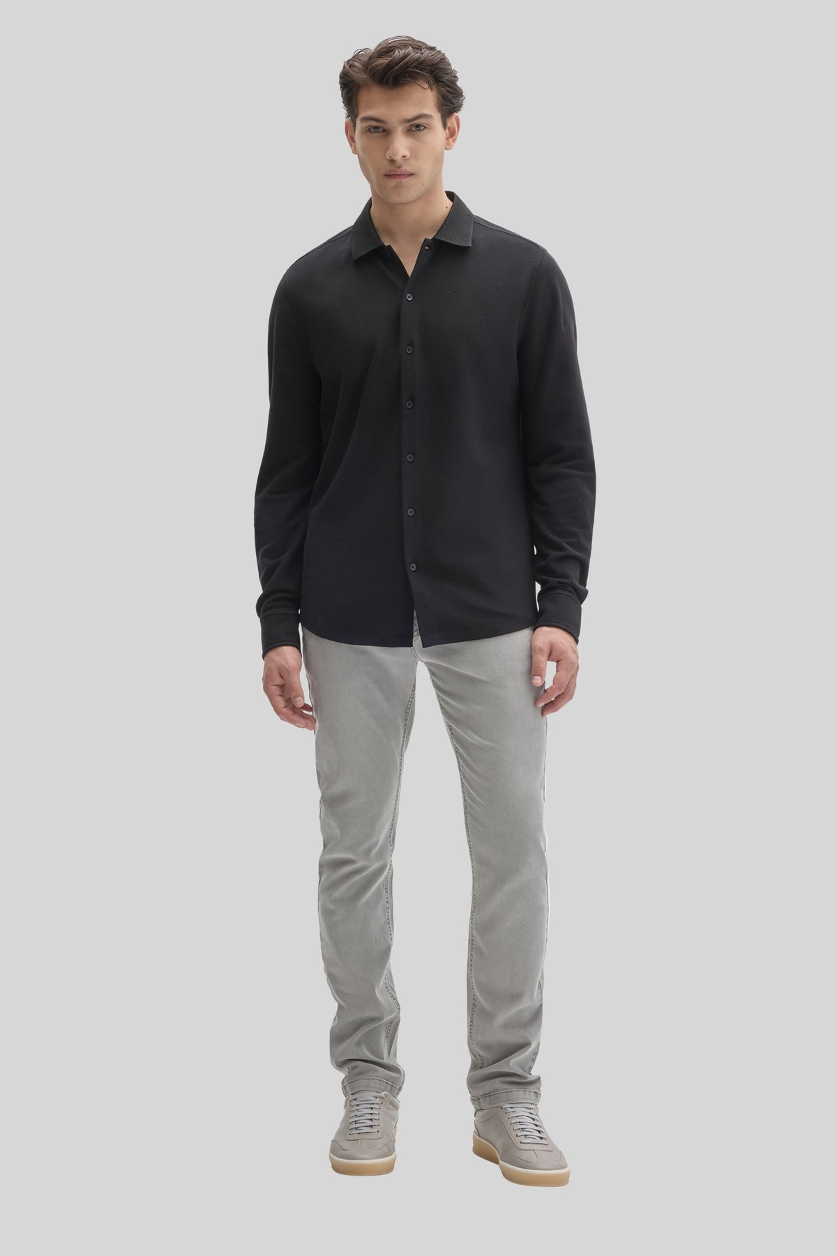 Black long sleeve button-up knit shirt with collar, worn with gray jeans and gray sneakers.