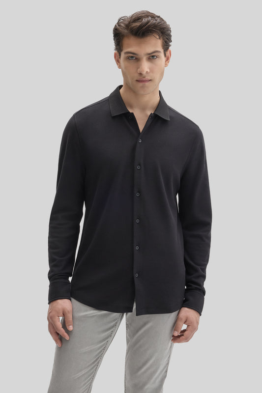 Man wearing black long sleeve knit shirt with button front and ribbed collar over gray pants.