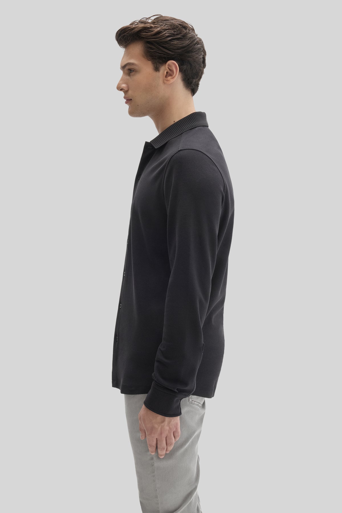 Man wearing black long sleeve knit shirt with ribbed collar and cuffs, paired with light gray pants.