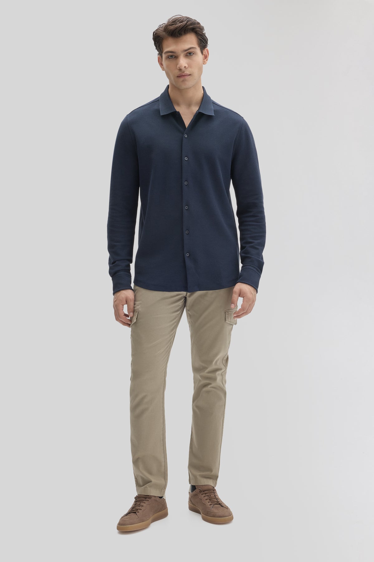 Navy long sleeve knit shirt with collar and button front, paired with beige cargo pants and brown shoes.
