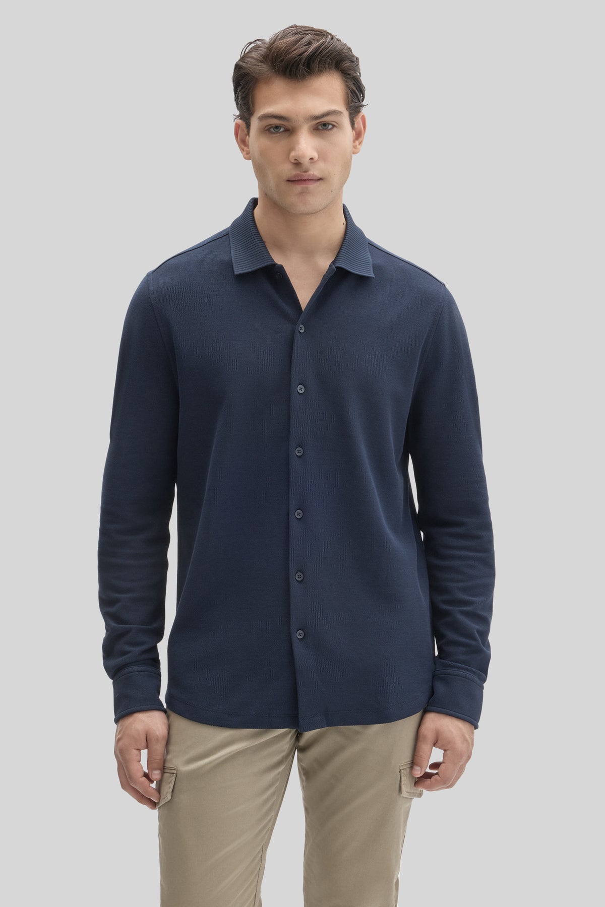 Man wearing dark navy long-sleeve button-up knit shirt with textured collar and khaki pants.
