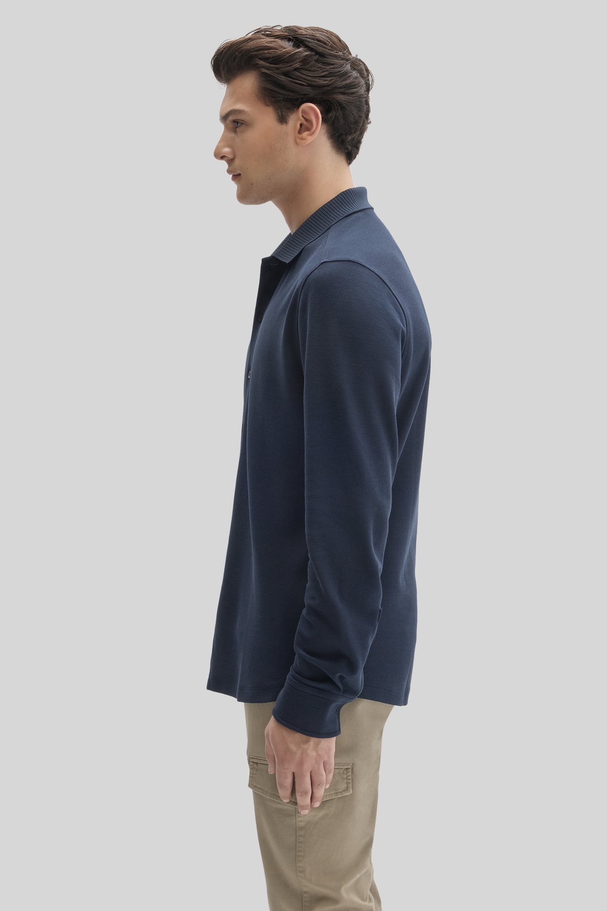 Man wearing navy blue long sleeve knit shirt with ribbed collar, paired with beige pants.