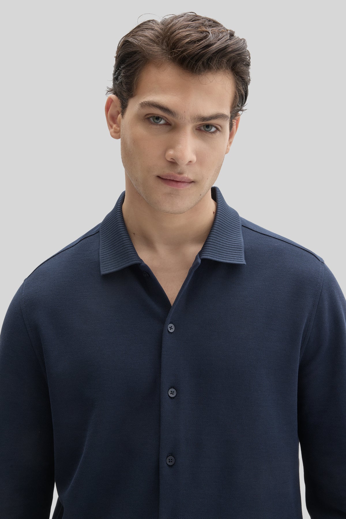 Navy knit shirt with long sleeves, collared neckline, and button front closure.