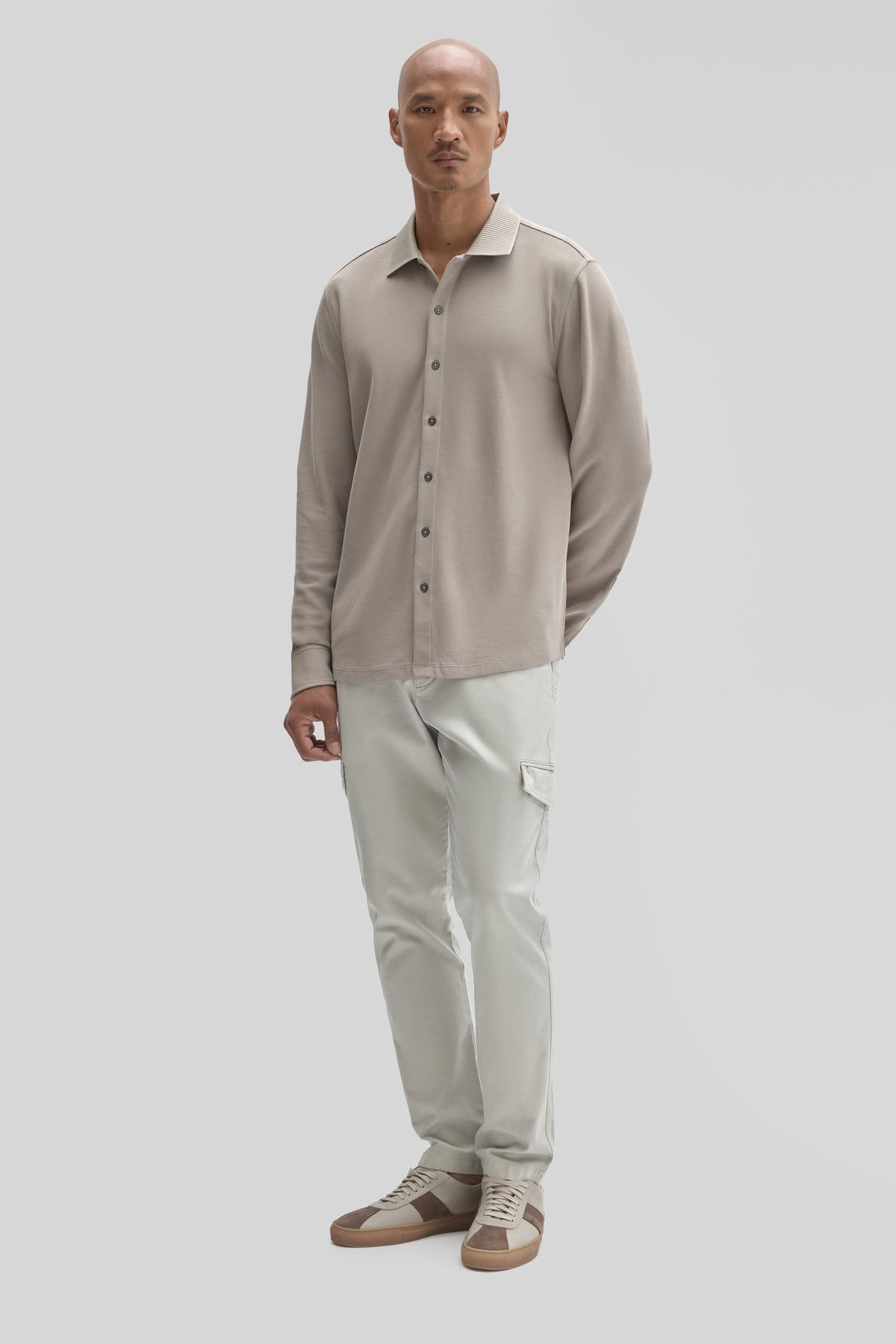 Man wearing beige long sleeve button-up knit shirt with cream cargo pants and tan sneakers.