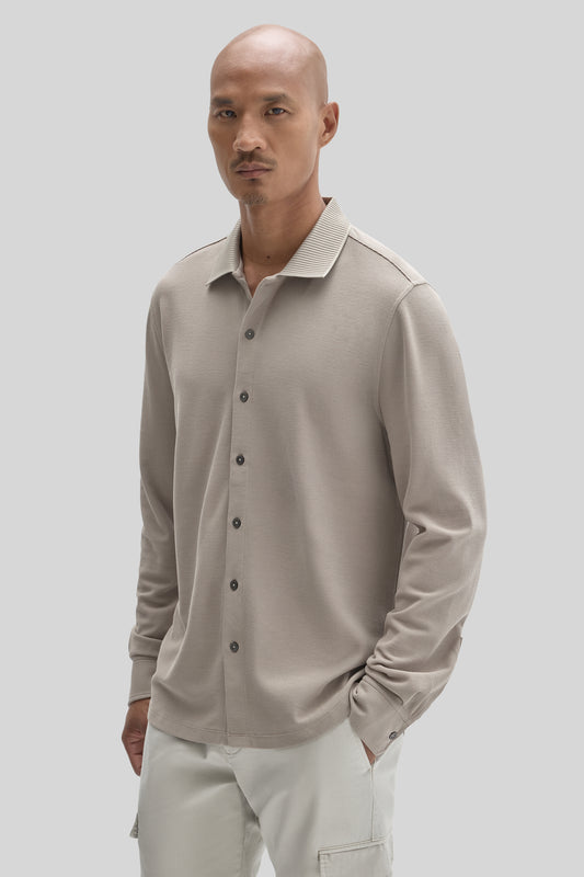 Beige long sleeve knit shirt with ribbed collar and button front on model wearing cream pants.