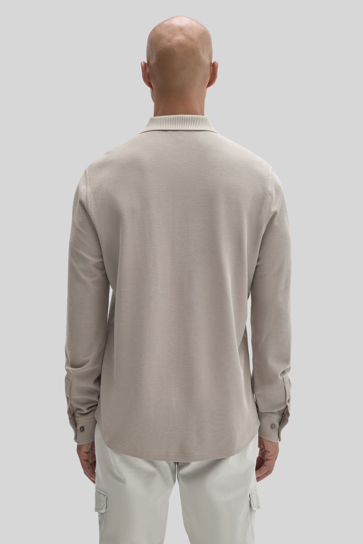Beige long sleeve knit shirt with ribbed collar and button cuffs, shown from back view on a model.