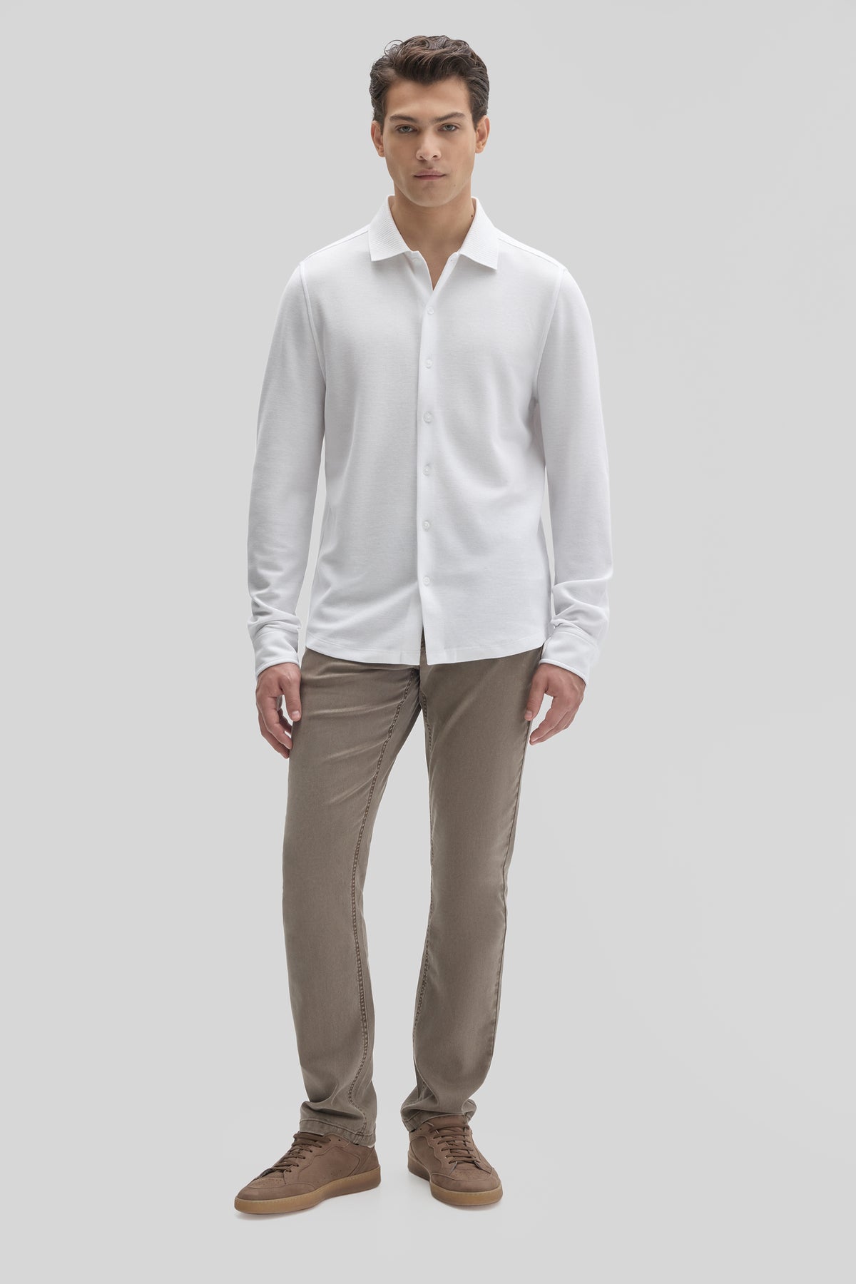 Man wearing white long sleeve button-up knit shirt with gray pants and brown shoes.
