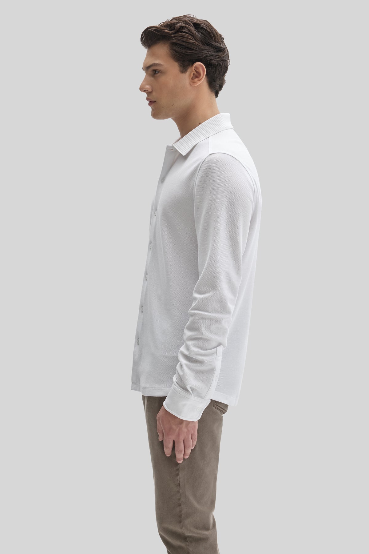 White long-sleeve knit shirt with ribbed collar and button front, worn by male model with khaki pants.