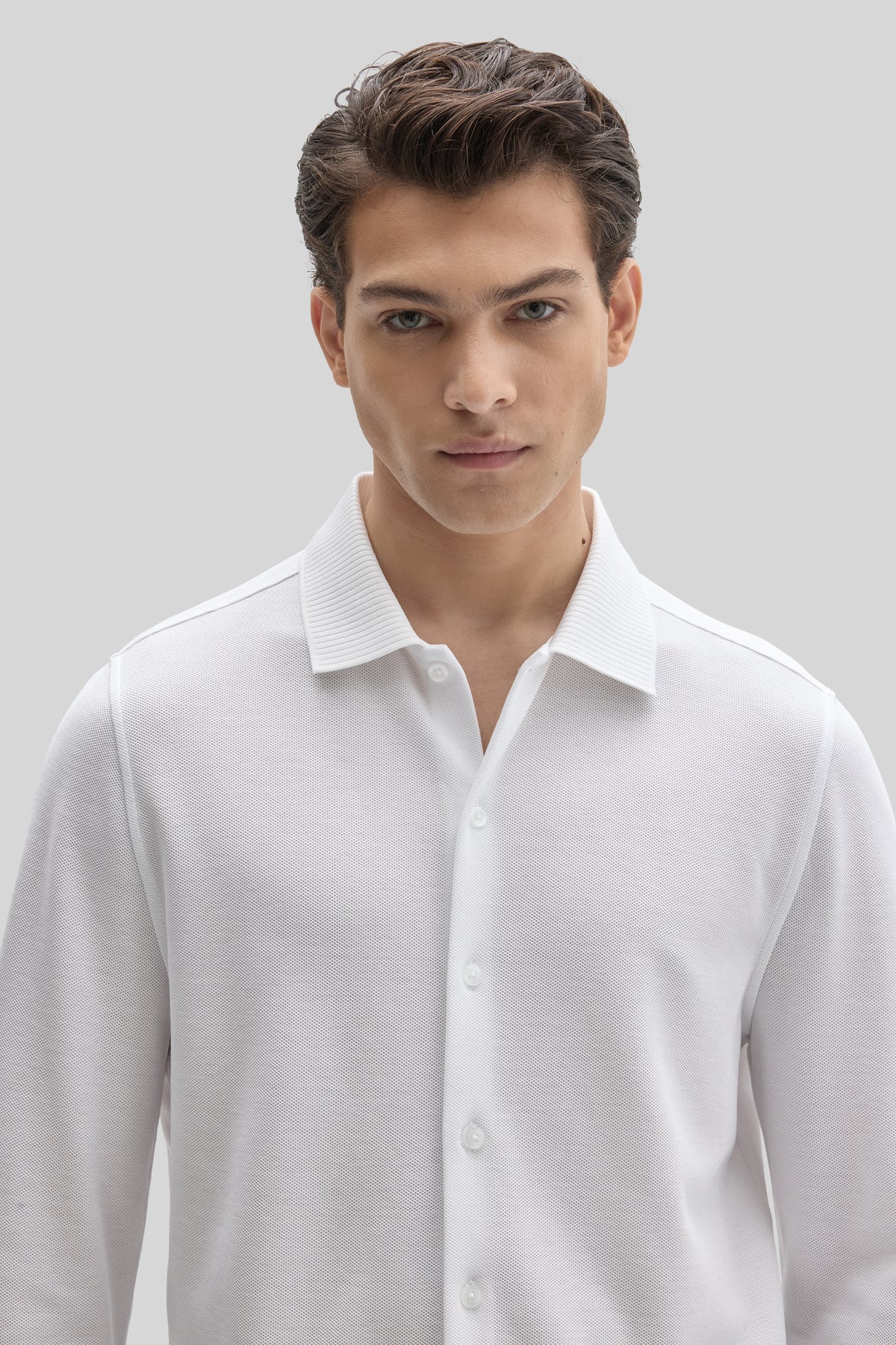 White long sleeve knit shirt with button front and ribbed collar on male model.