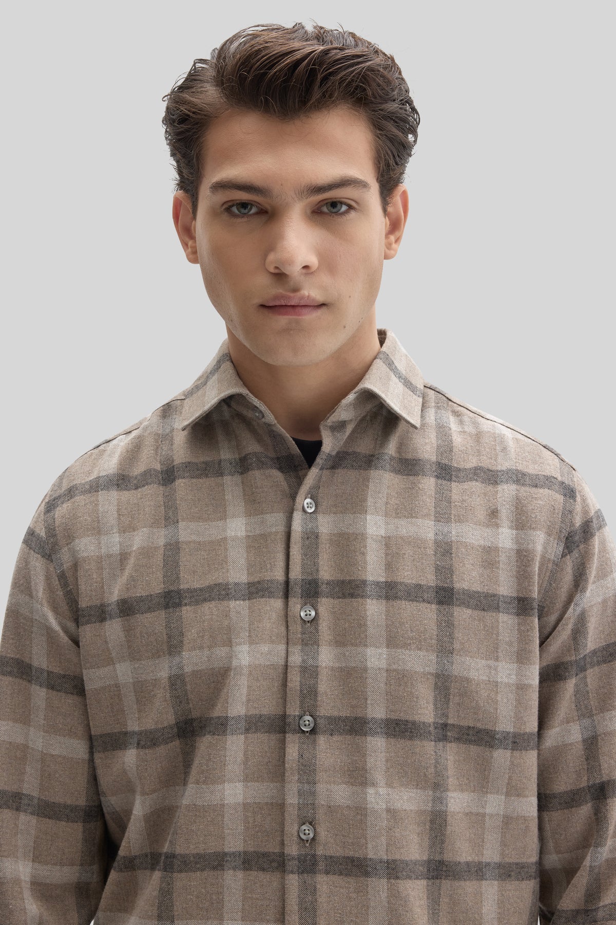 Beige and gray plaid flannel shirt with button front, displayed on a model against a neutral background.