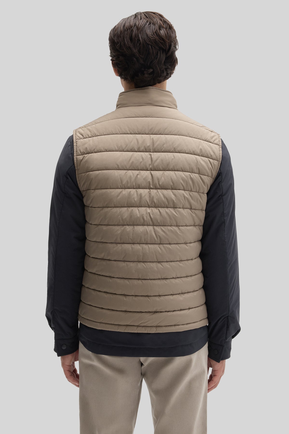 Beige quilted vest with black long-sleeve shirt and beige pants, shown from back view.