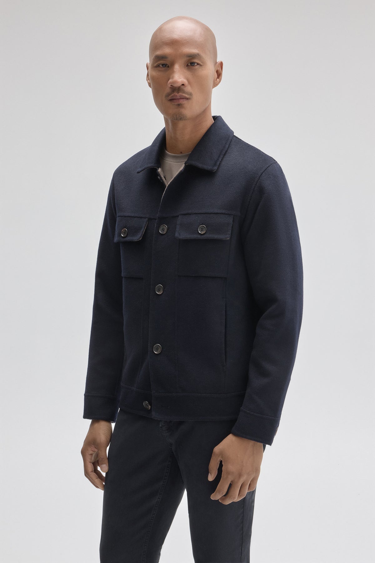 Navy buttoned jacket with collared neckline and multiple front pockets, worn over a gray shirt.