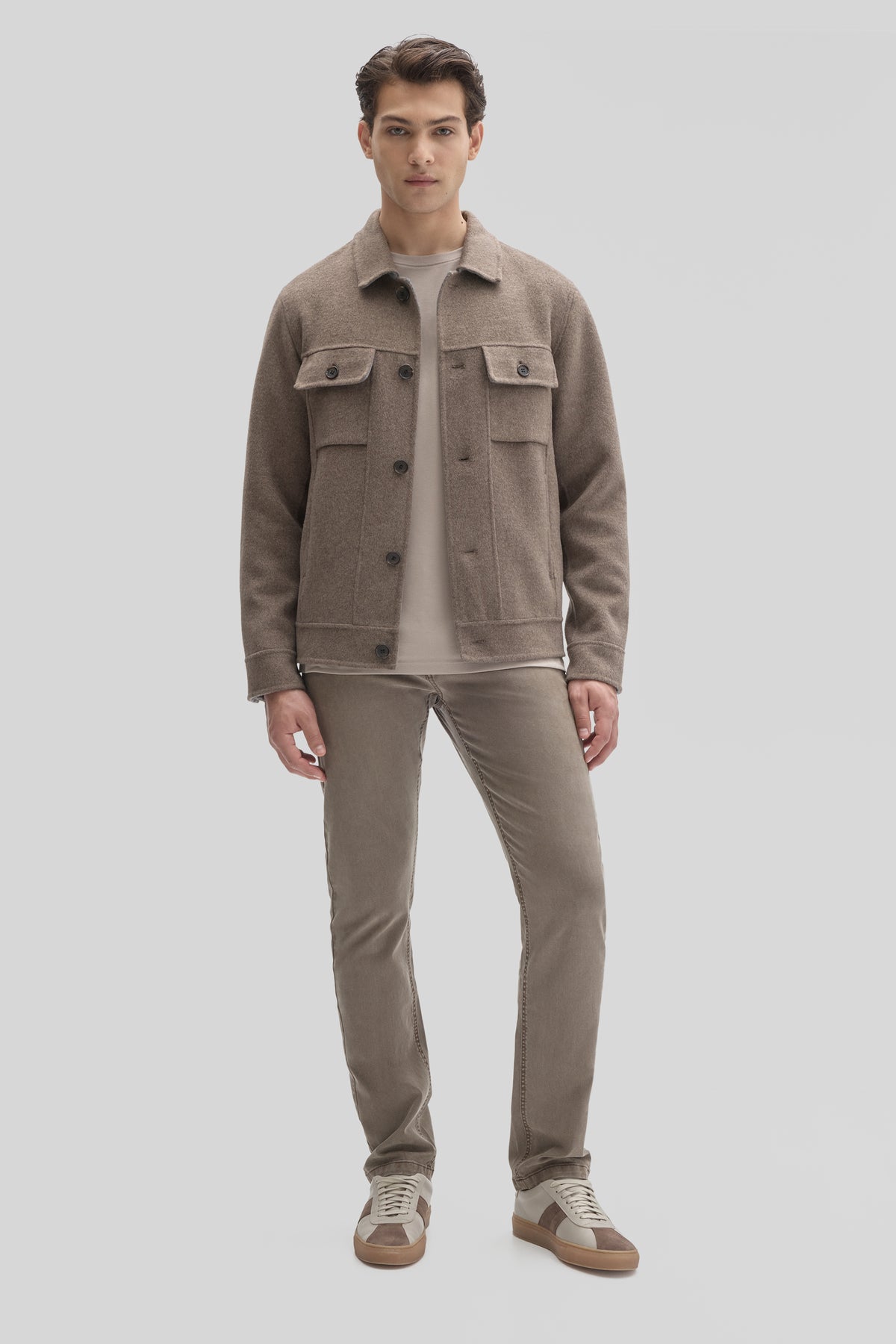 Beige buttoned jacket with chest pockets worn over a light gray shirt and matching pants.