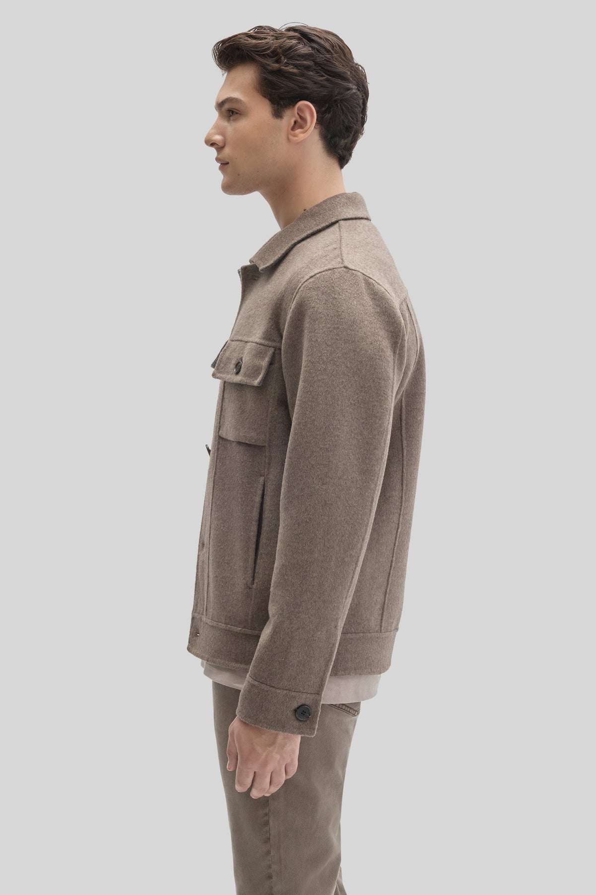 Beige wool buttoned jacket with chest pockets, shown on male model in side profile.