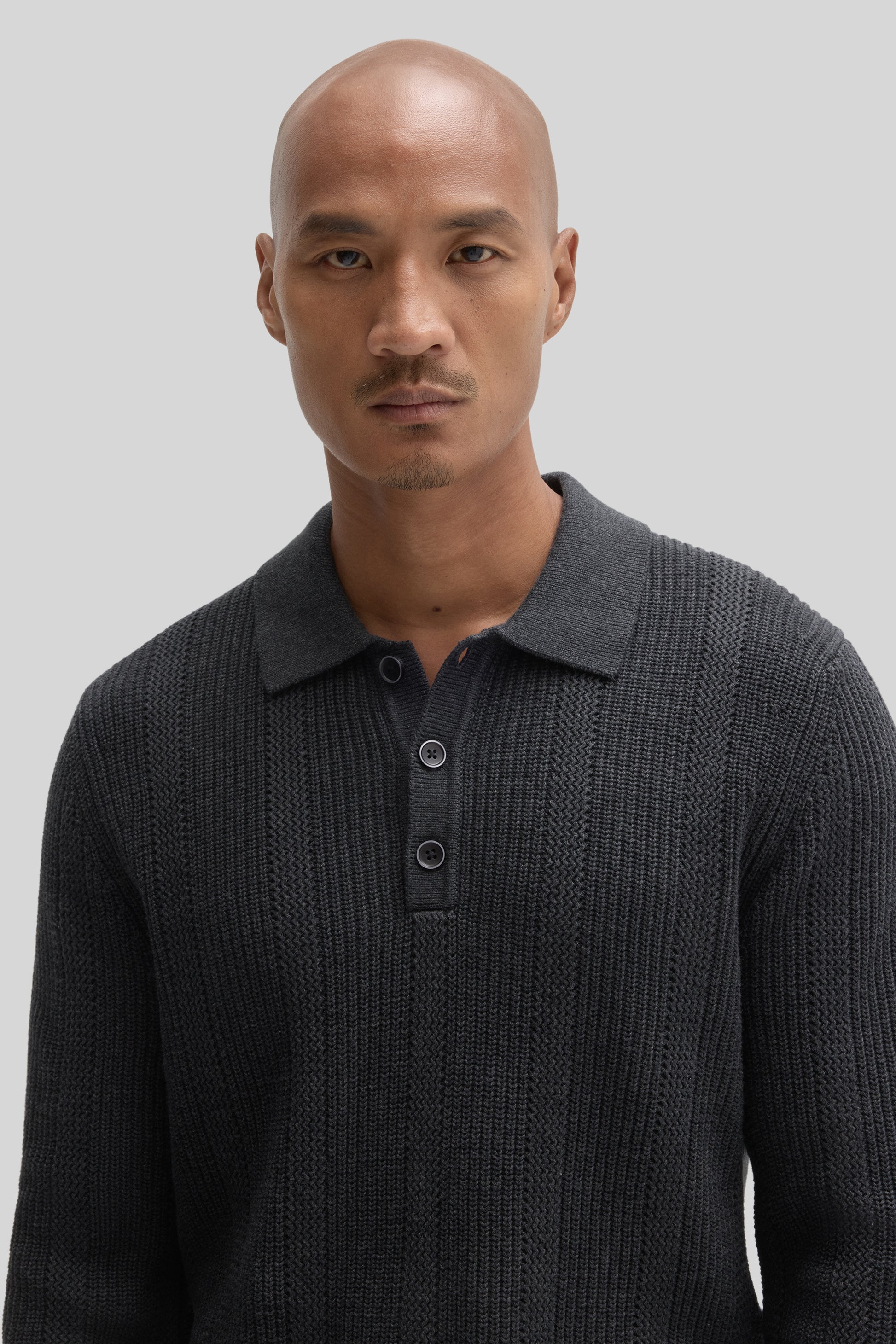 Charcoal gray sweater polo with ribbed texture and button placket at neckline, worn by model against neutral background.