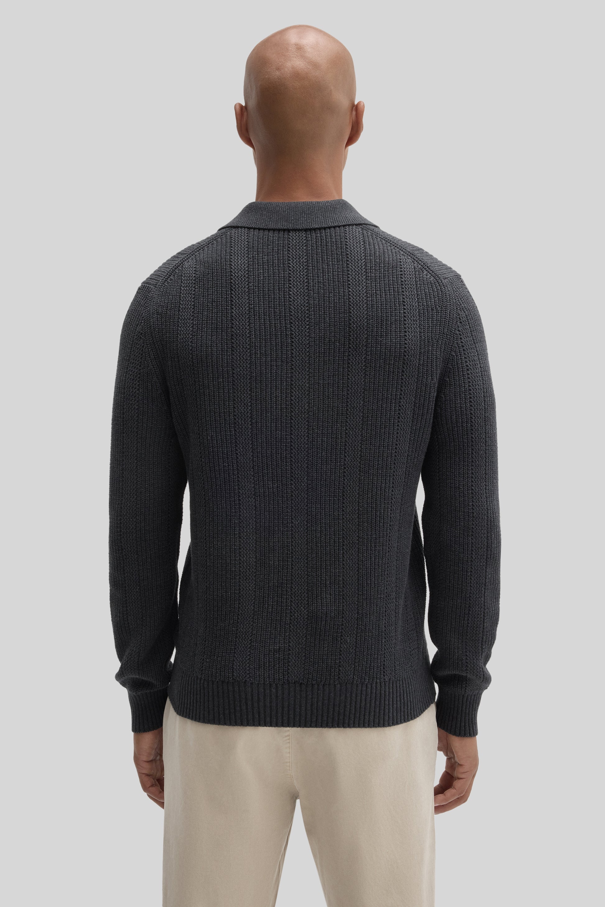 Man wearing dark gray ribbed knit sweater polo with collared neckline, viewed from back.