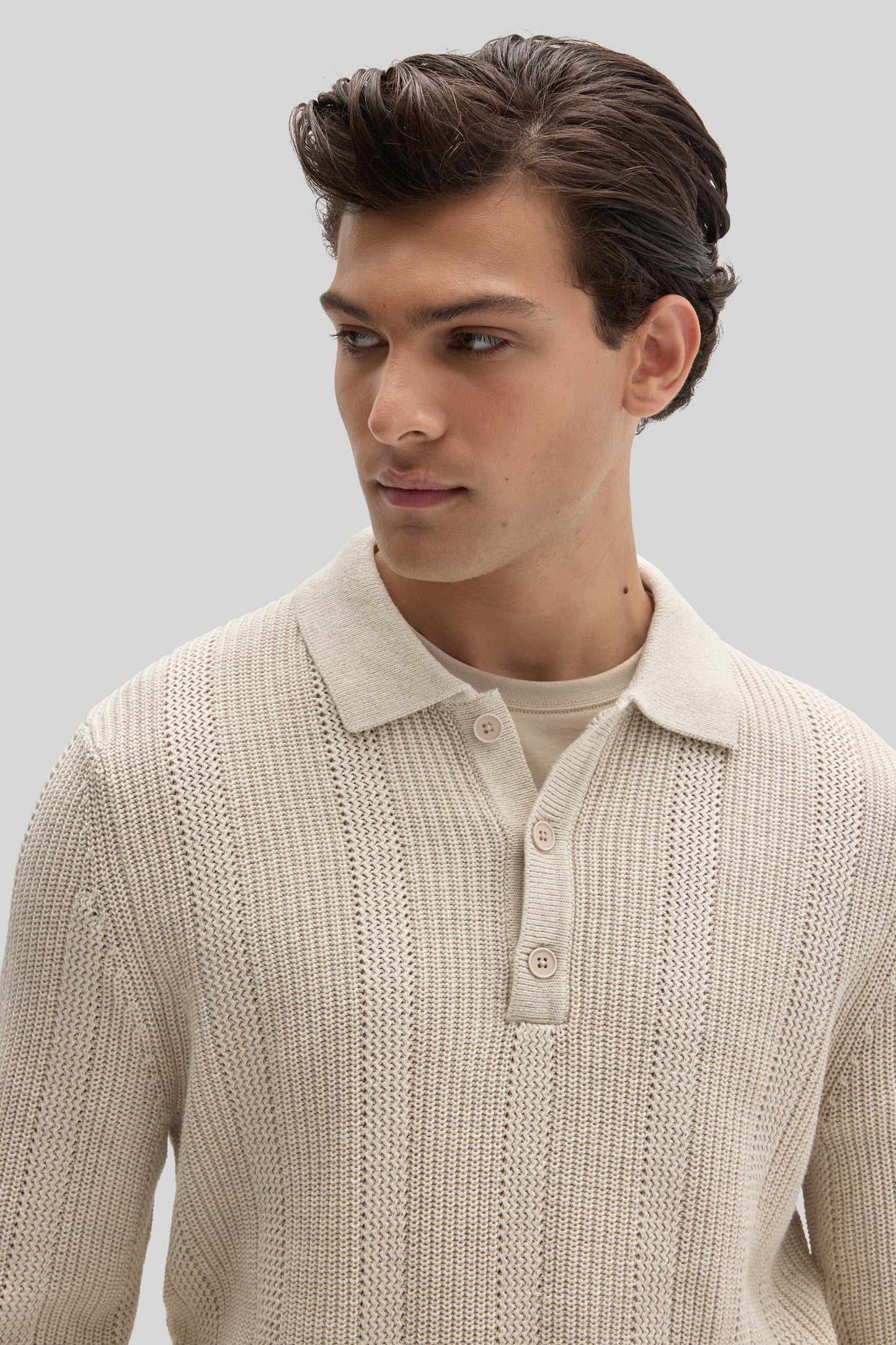 Cream knit polo sweater with textured pattern and button placket worn by model against neutral background.