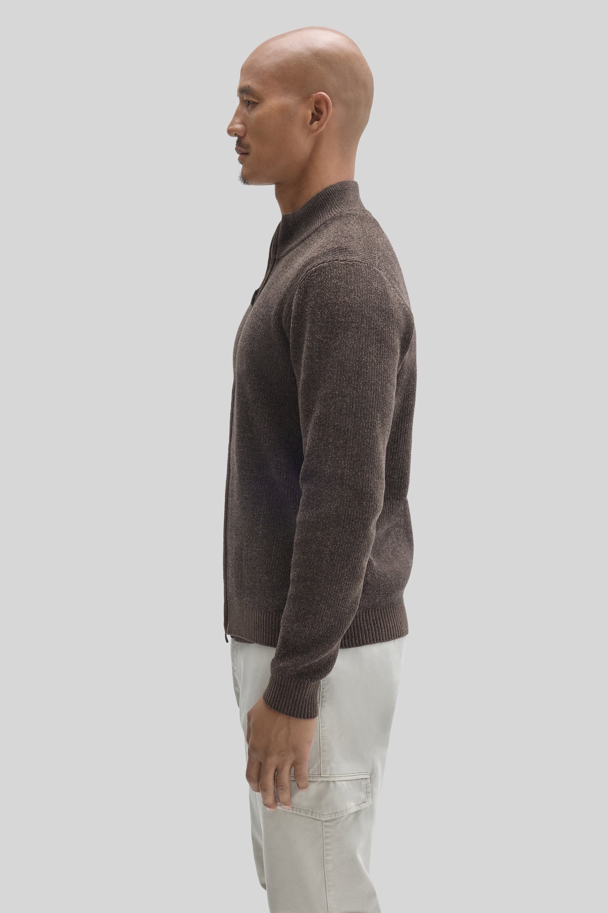 Charcoal gray full-zip mock neck sweater with ribbed cuffs and hem, worn with cream-colored pants.