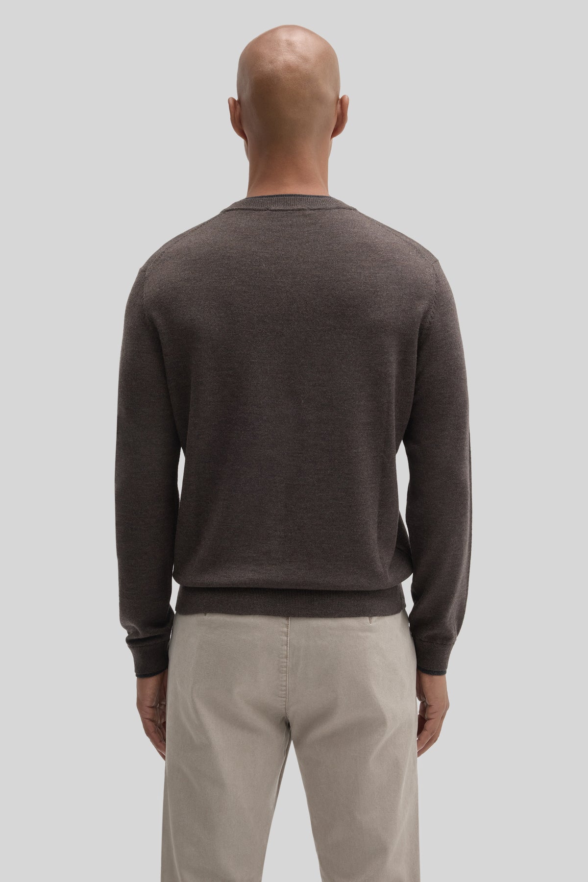 Charcoal crewneck sweater with long sleeves worn with beige pants, shown from back view.