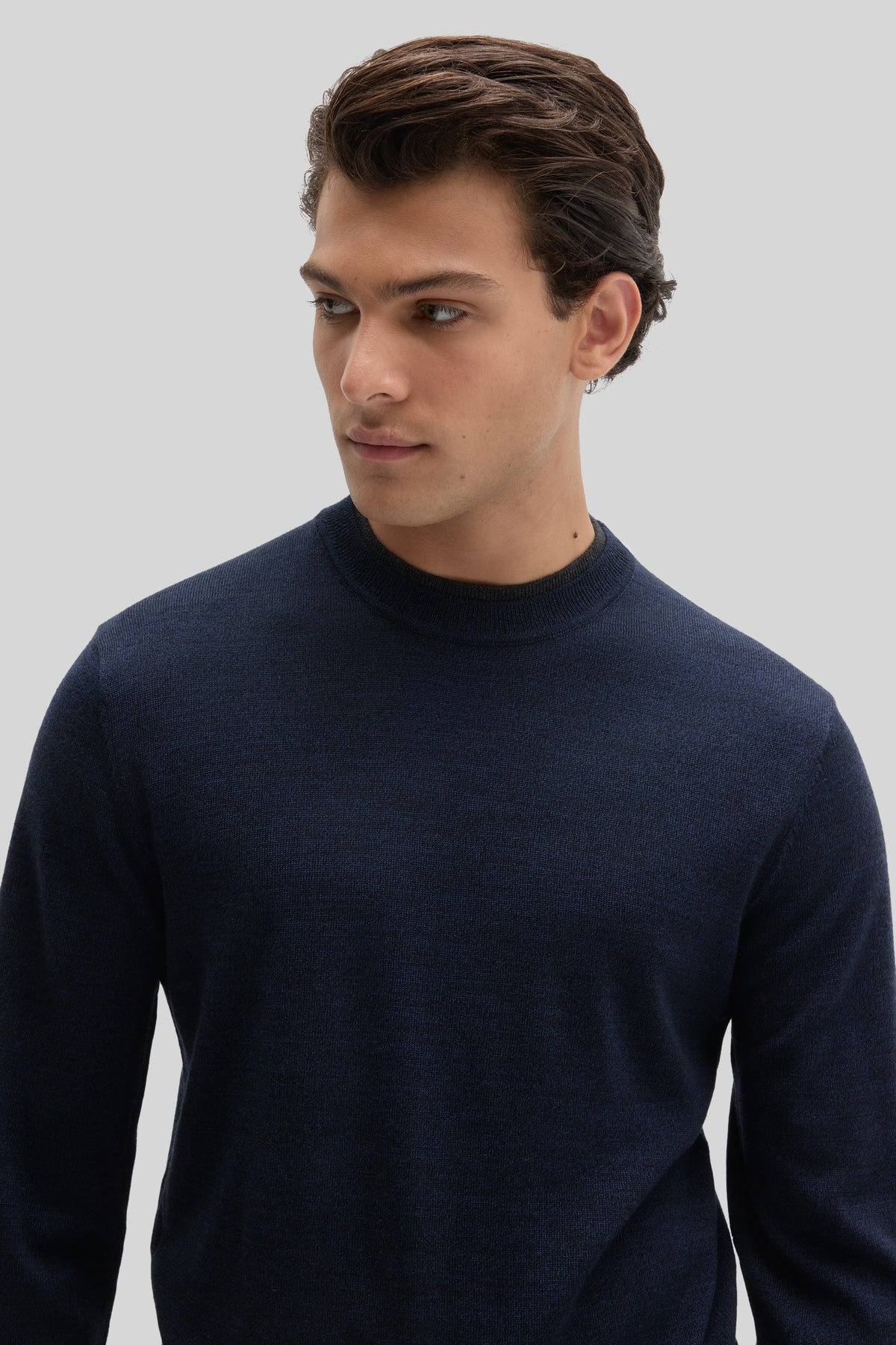 Man wearing dark navy crewneck sweater with ribbed neckline and long sleeves.