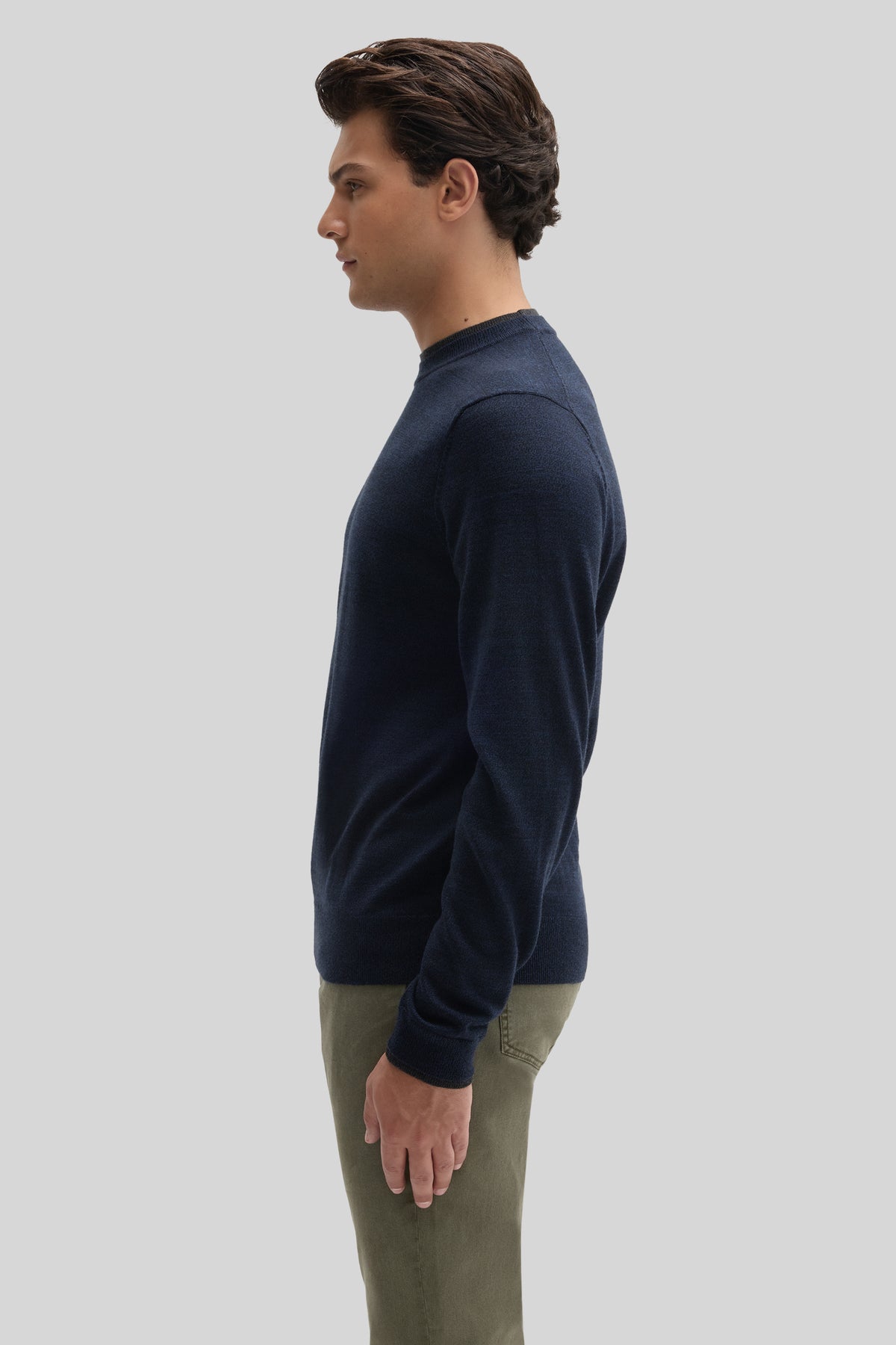 Man wearing navy crewneck sweater with long sleeves and ribbed cuffs, styled with khaki pants.