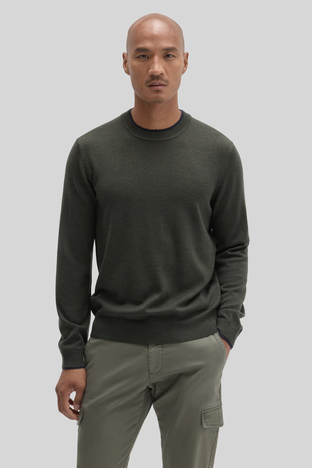 Olive green crewneck sweater with long sleeves worn with khaki cargo pants.